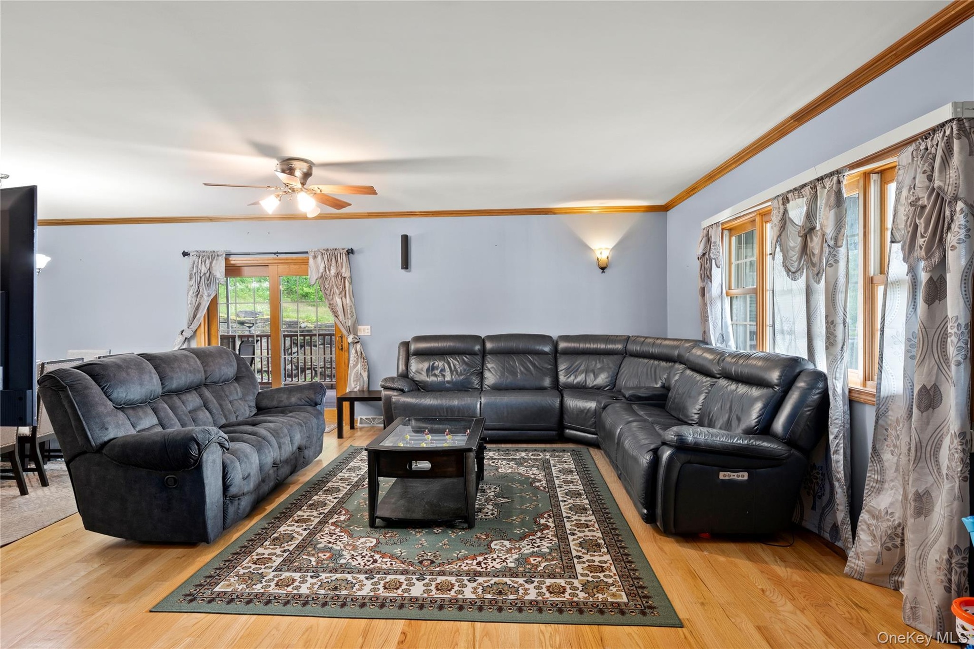 Living area featuring a ceiling fan, wood finished floors, and ornamental molding