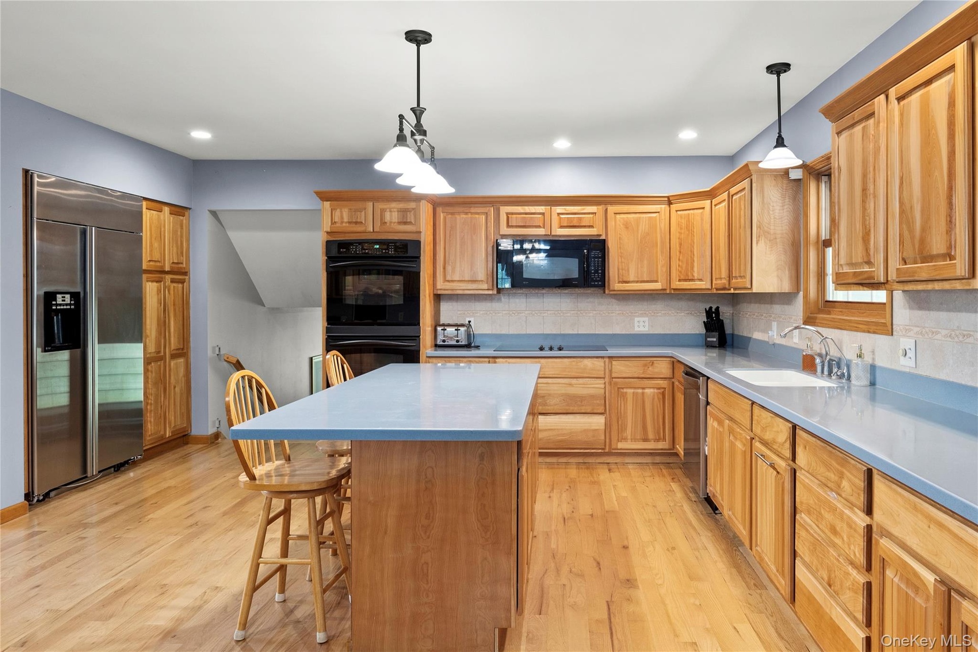 Kitchen with a kitchen breakfast bar, light wood-style flooring, decorative backsplash, and recessed lighting