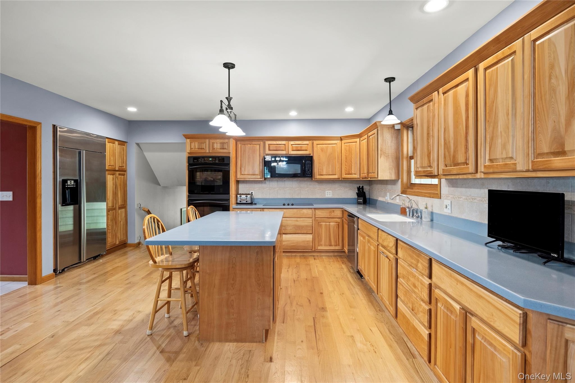 Kitchen featuring a breakfast bar area, light wood finished floors, backsplash, and recessed lighting