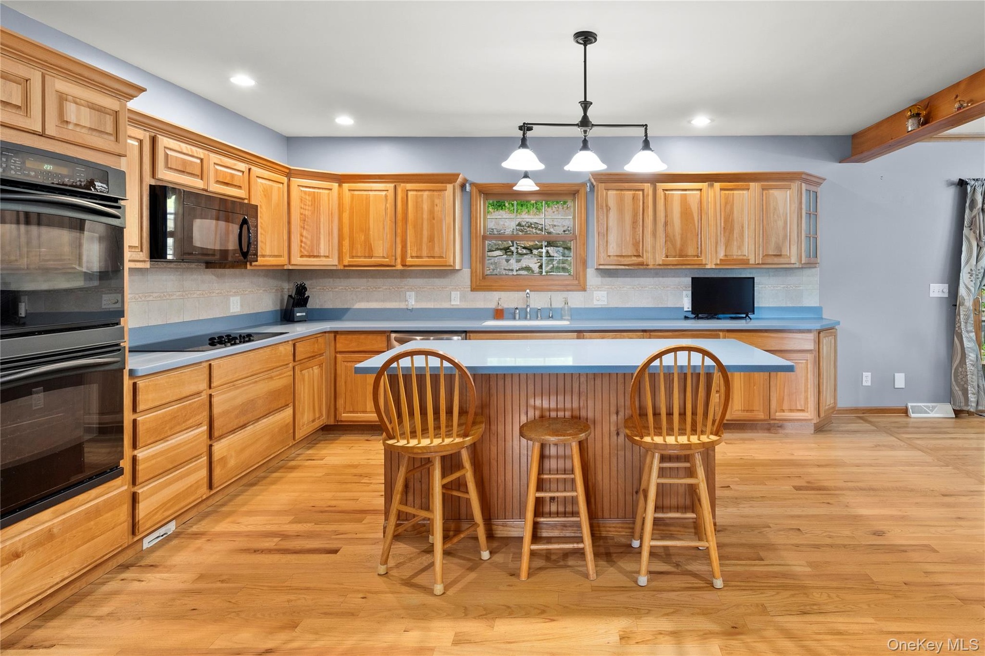 Kitchen featuring an island/breakfast bar, light wood-type flooring, tasteful backsplash, and recessed lighting