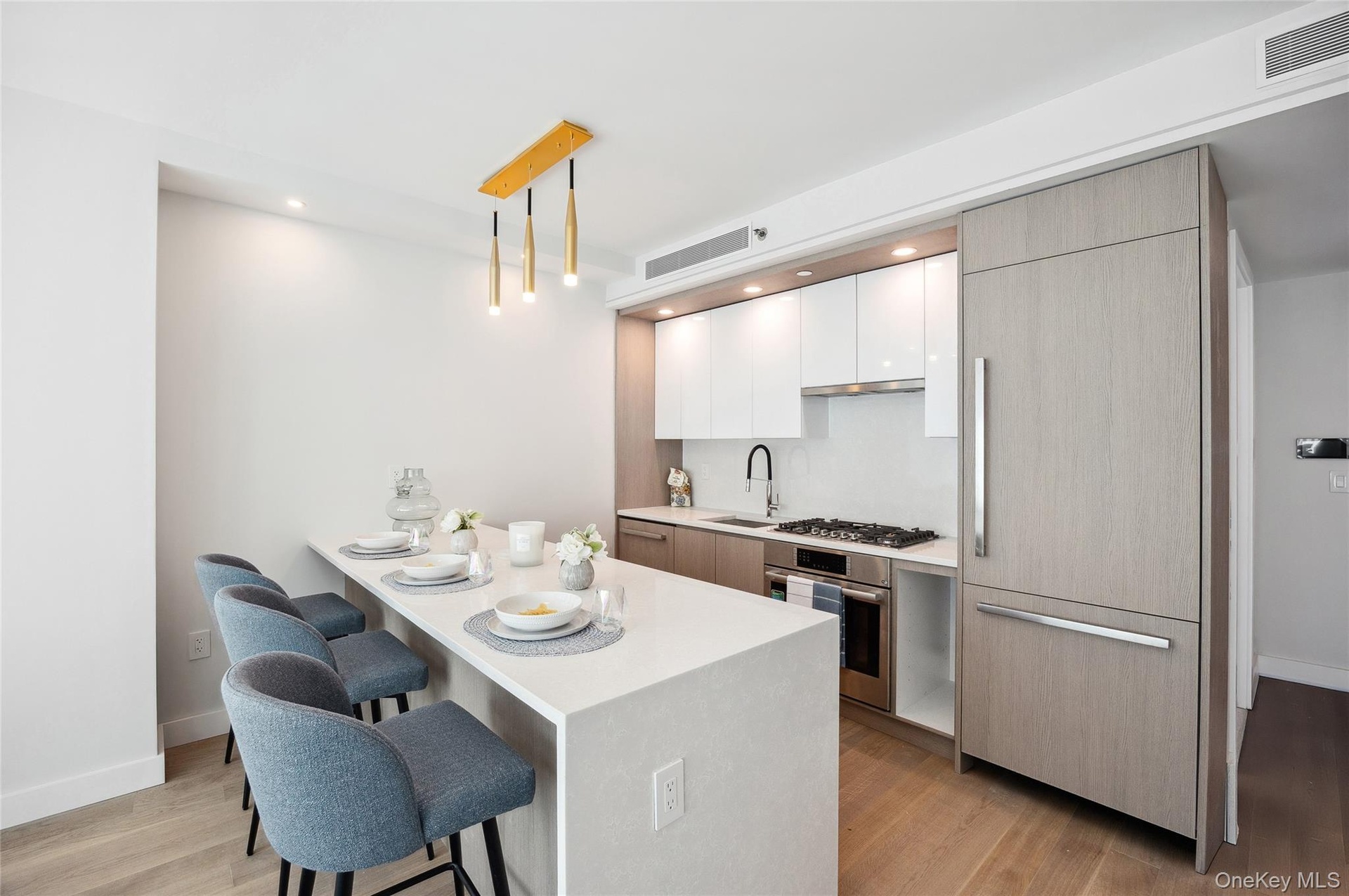Kitchen featuring appliances with stainless steel finishes, a kitchen bar, modern cabinets, light wood-type flooring, and light countertops