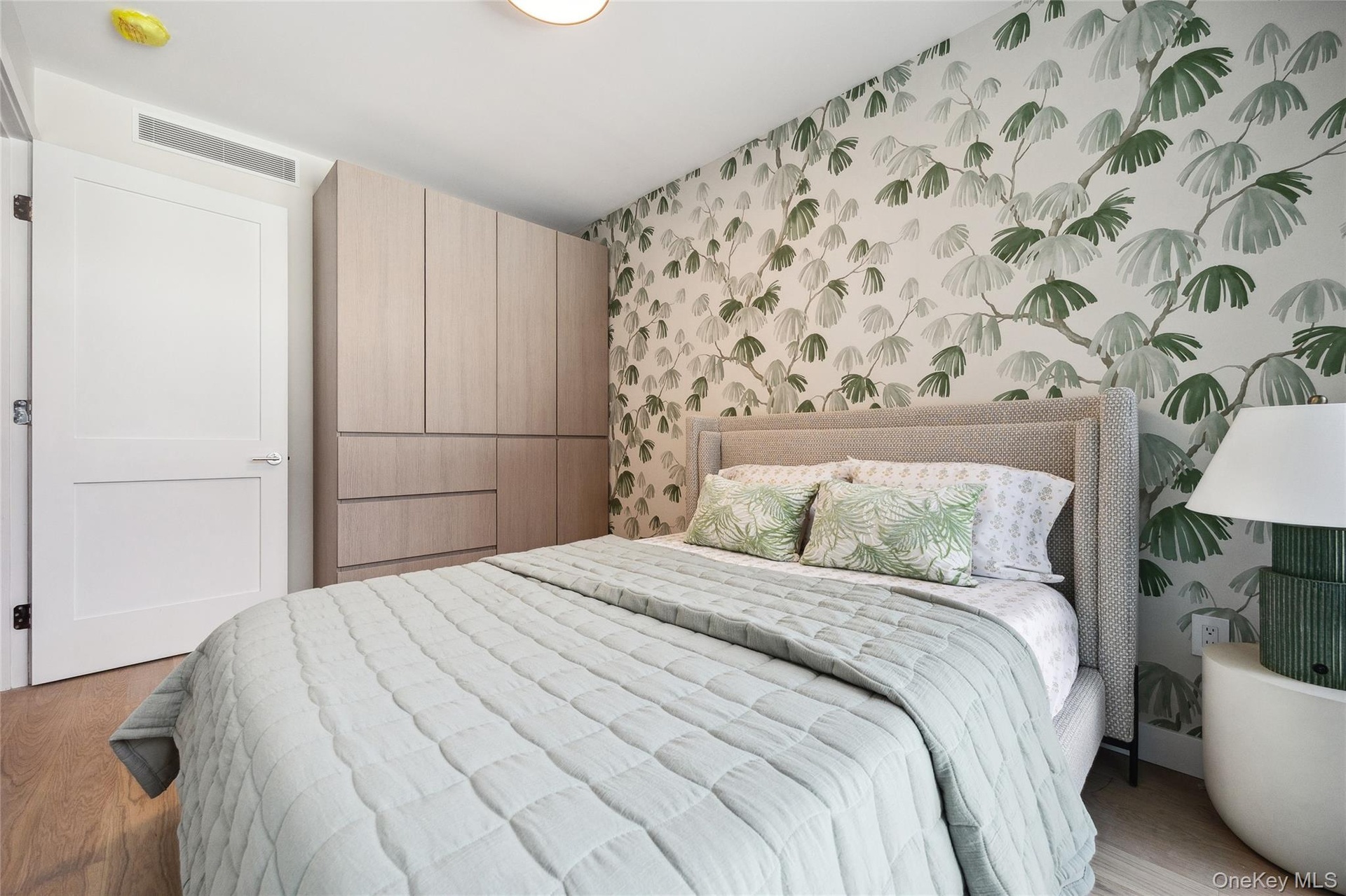 Bedroom with wallpapered walls and wood finished floors