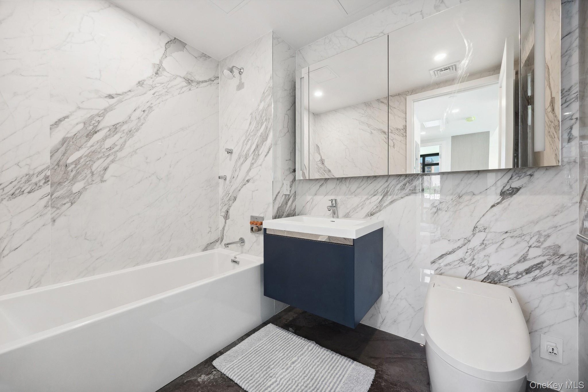 Full bathroom with tile walls, toilet, bathtub / shower combination, and vanity