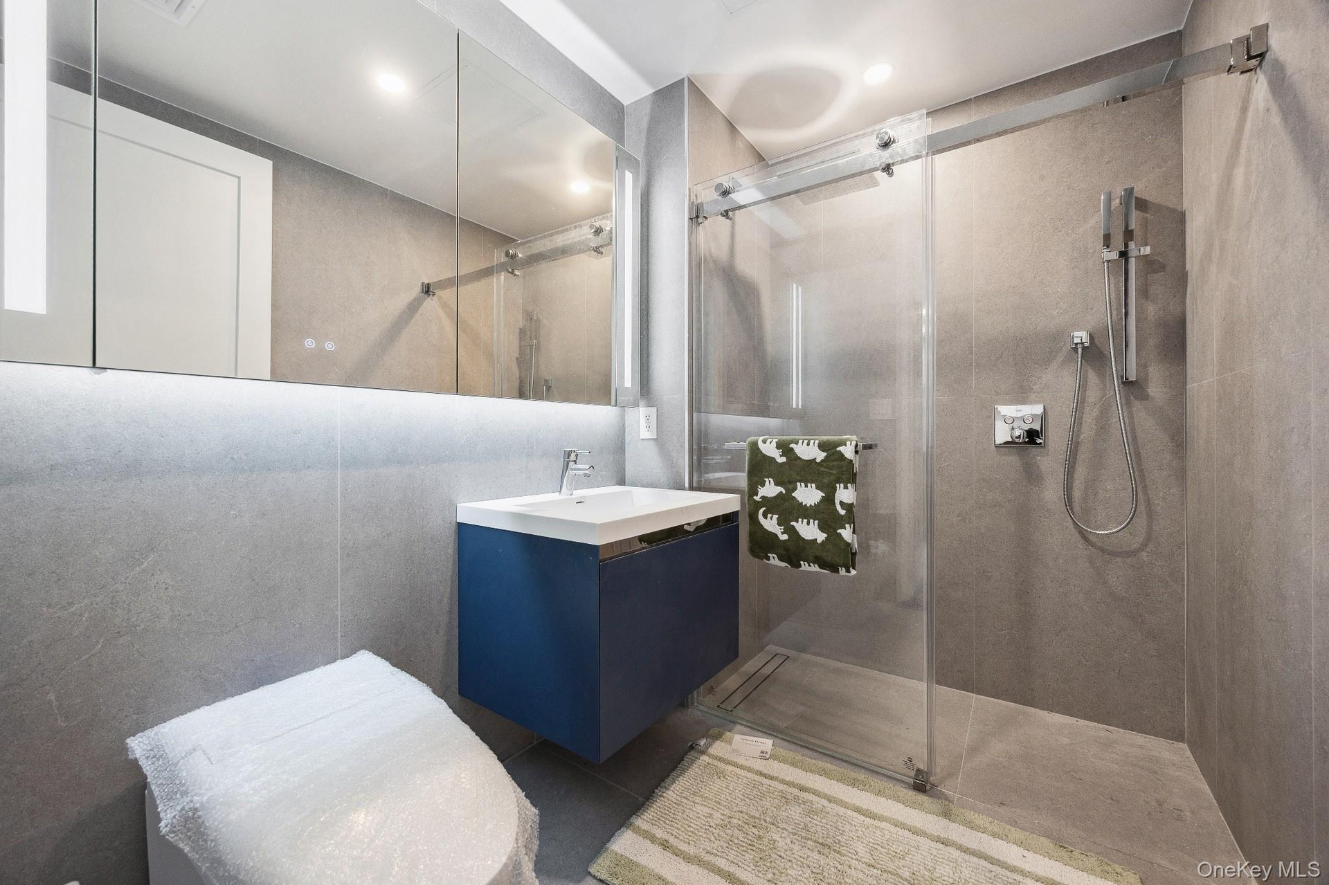 Bathroom featuring tiled shower and vanity