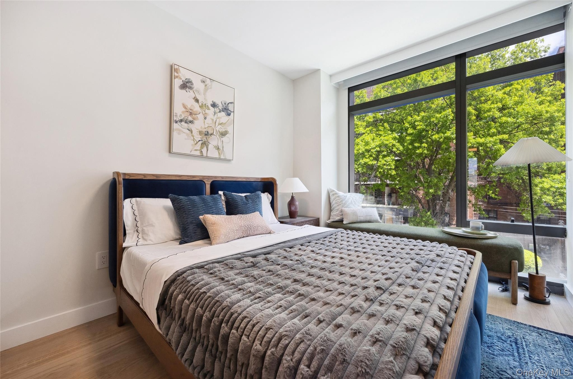 Bedroom with multiple windows, baseboards, wood finished floors, and expansive windows