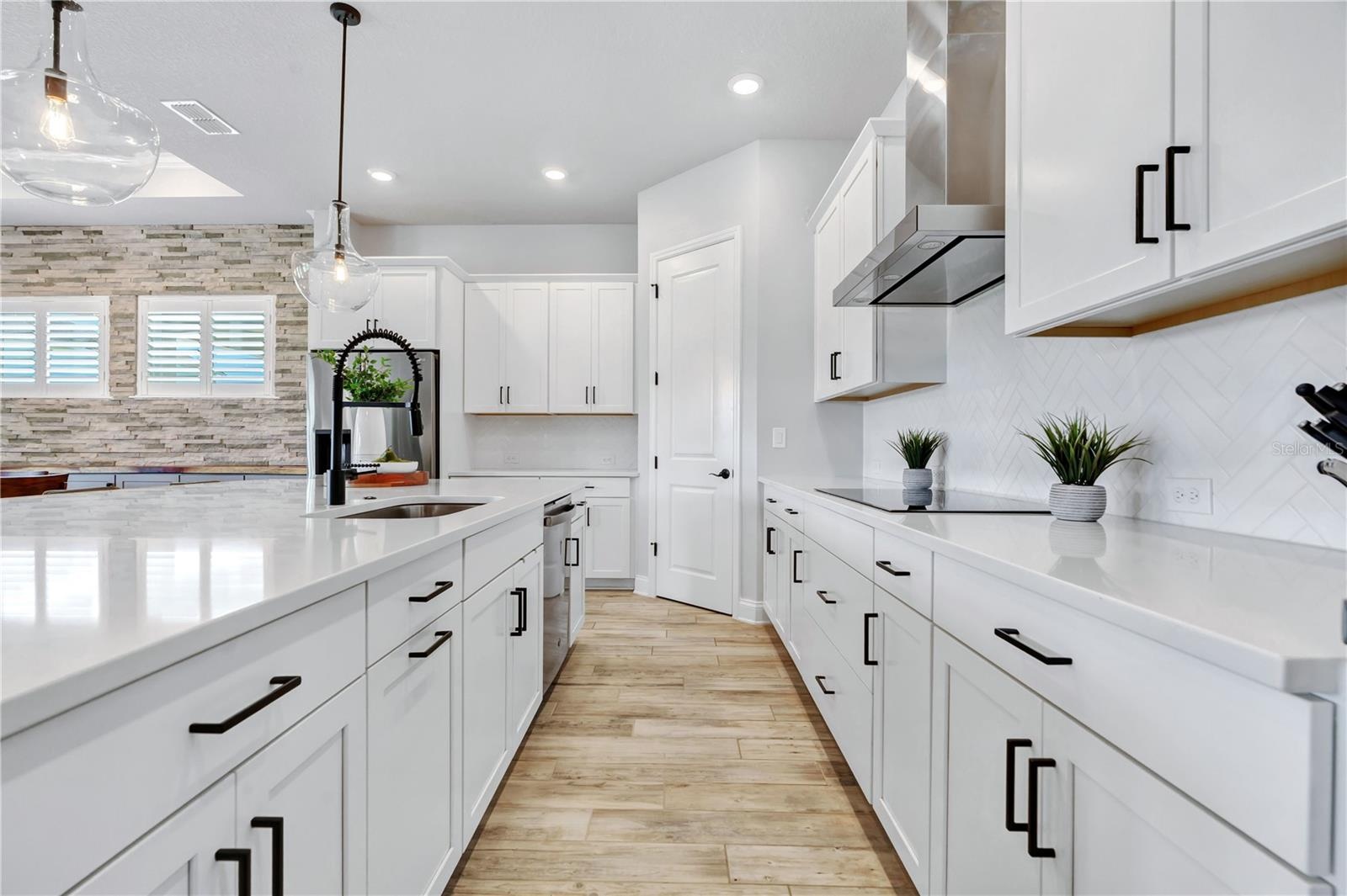 White 42 inch cabinetry, stainless range hood, and herringbone backsplash. Abundant storage plus a walk in pantry.