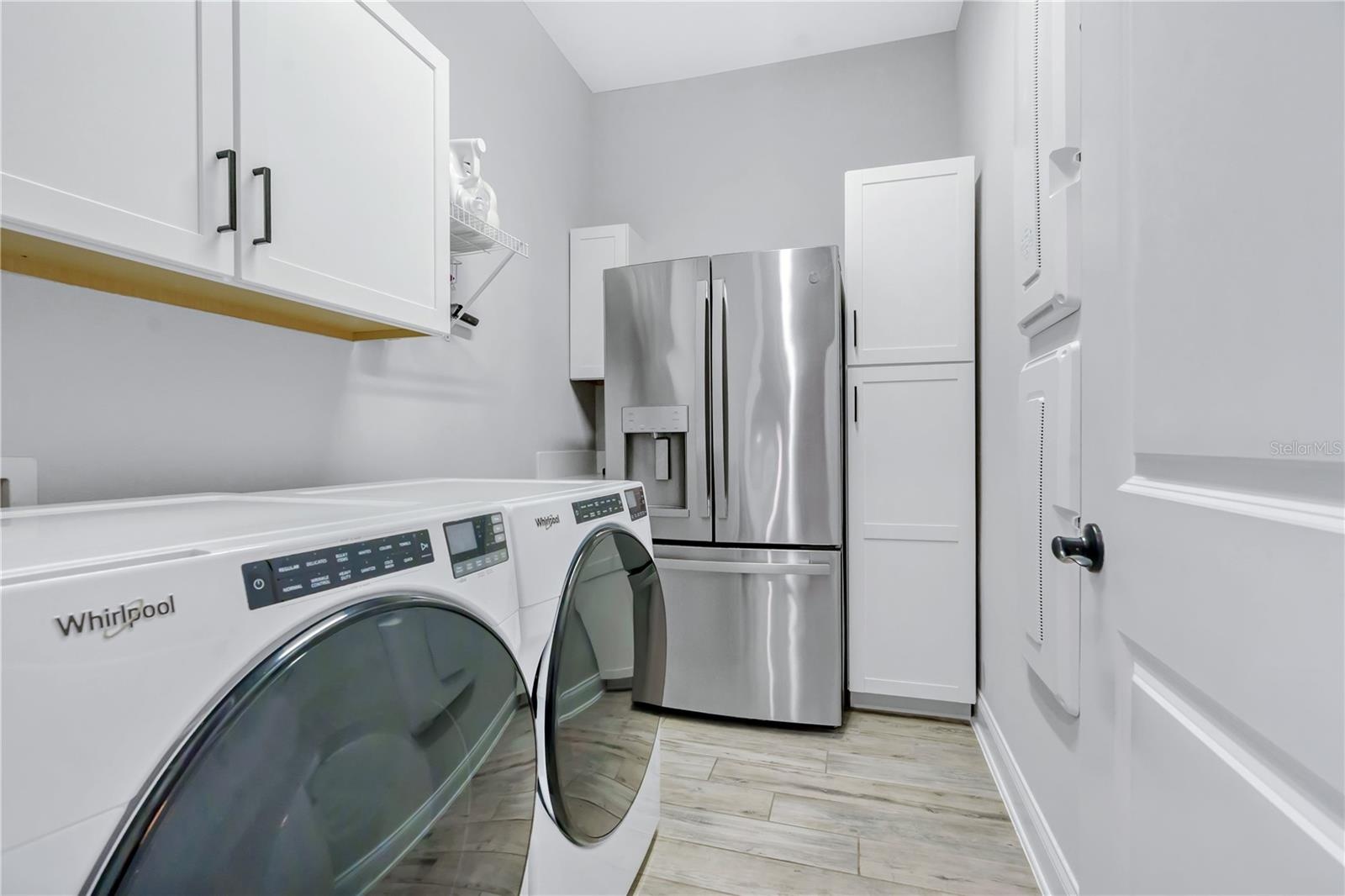 Laundry room with storage cabinetry and space for a second refrigerator, plus a mud room drop zone near the entry.