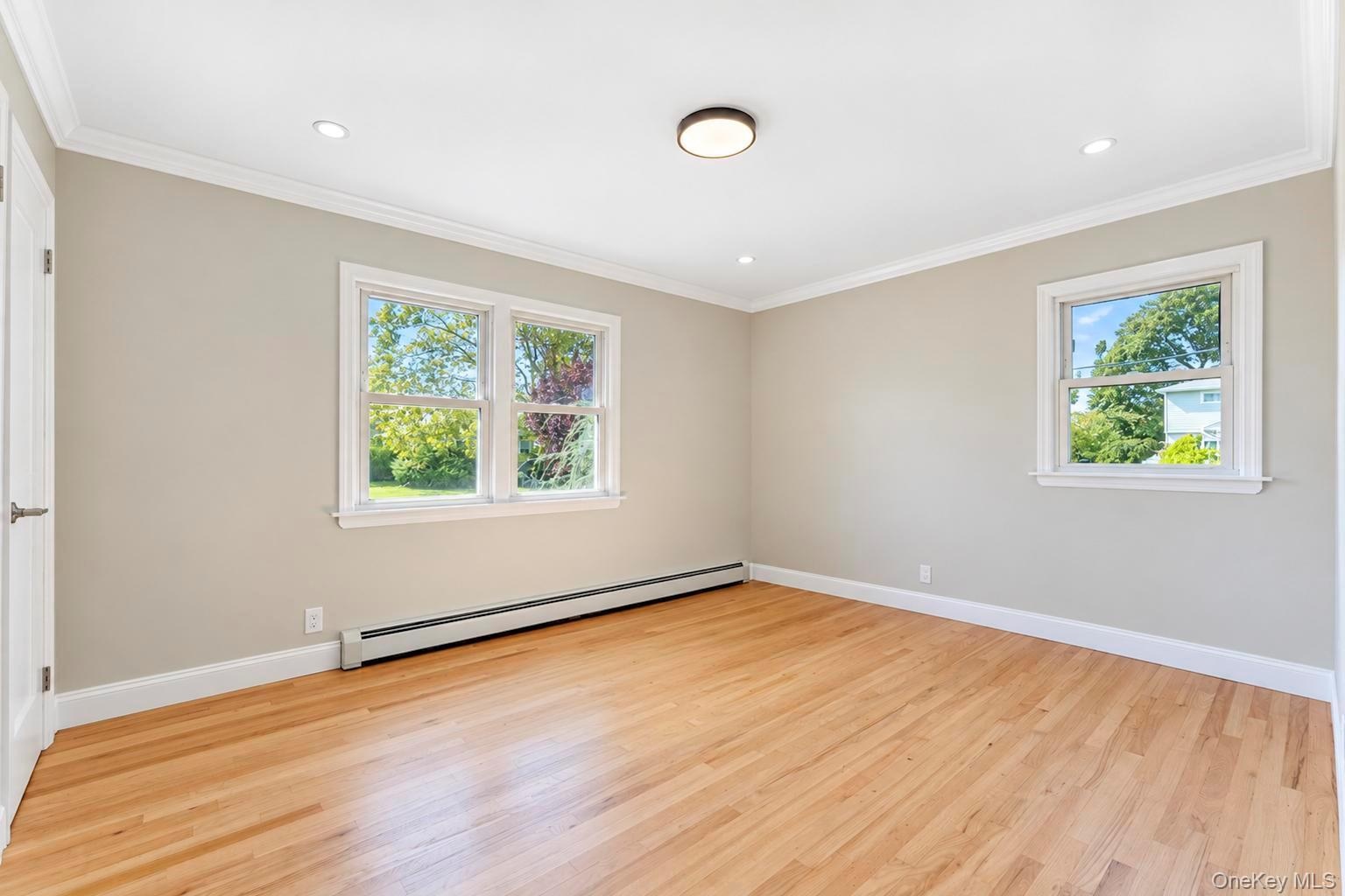 Neutral-toned interior featuring wood-finish flooring, crown molding, recessed lighting, and multi-pane windows