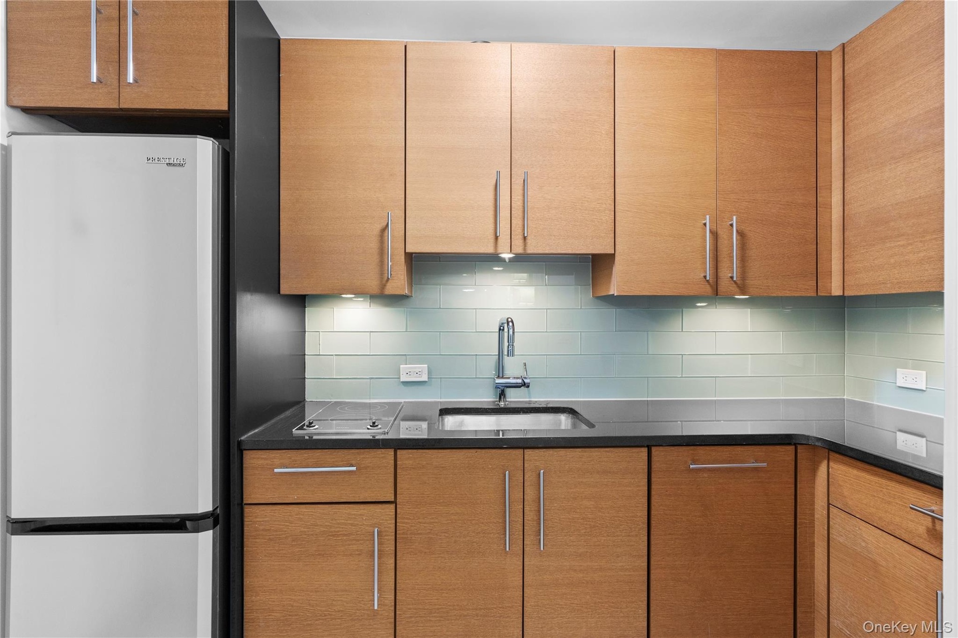 Kitchen with freestanding refrigerator, a sink, and backsplash