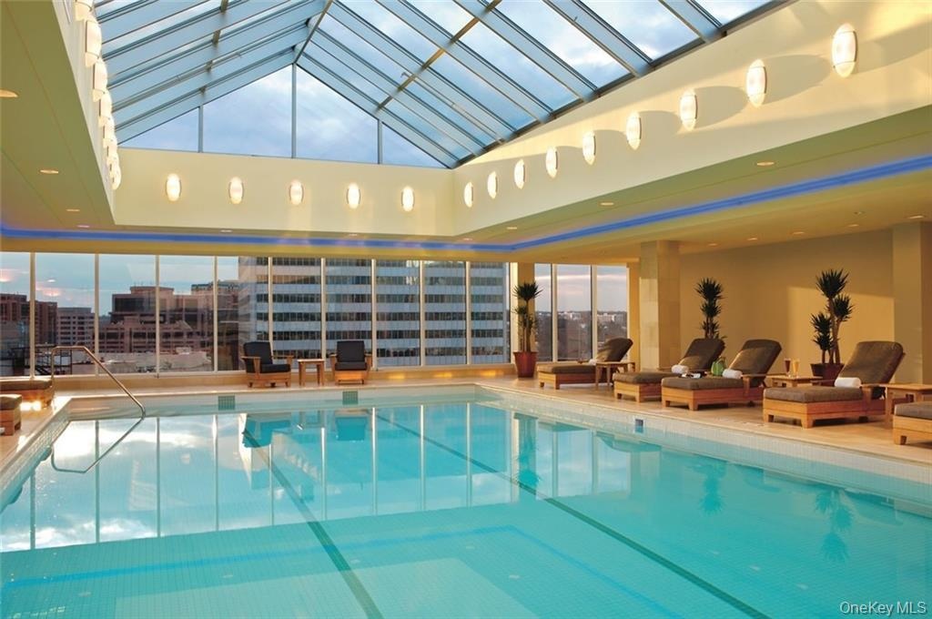 Pool featuring a view of city, glass enclosure, and a patio area