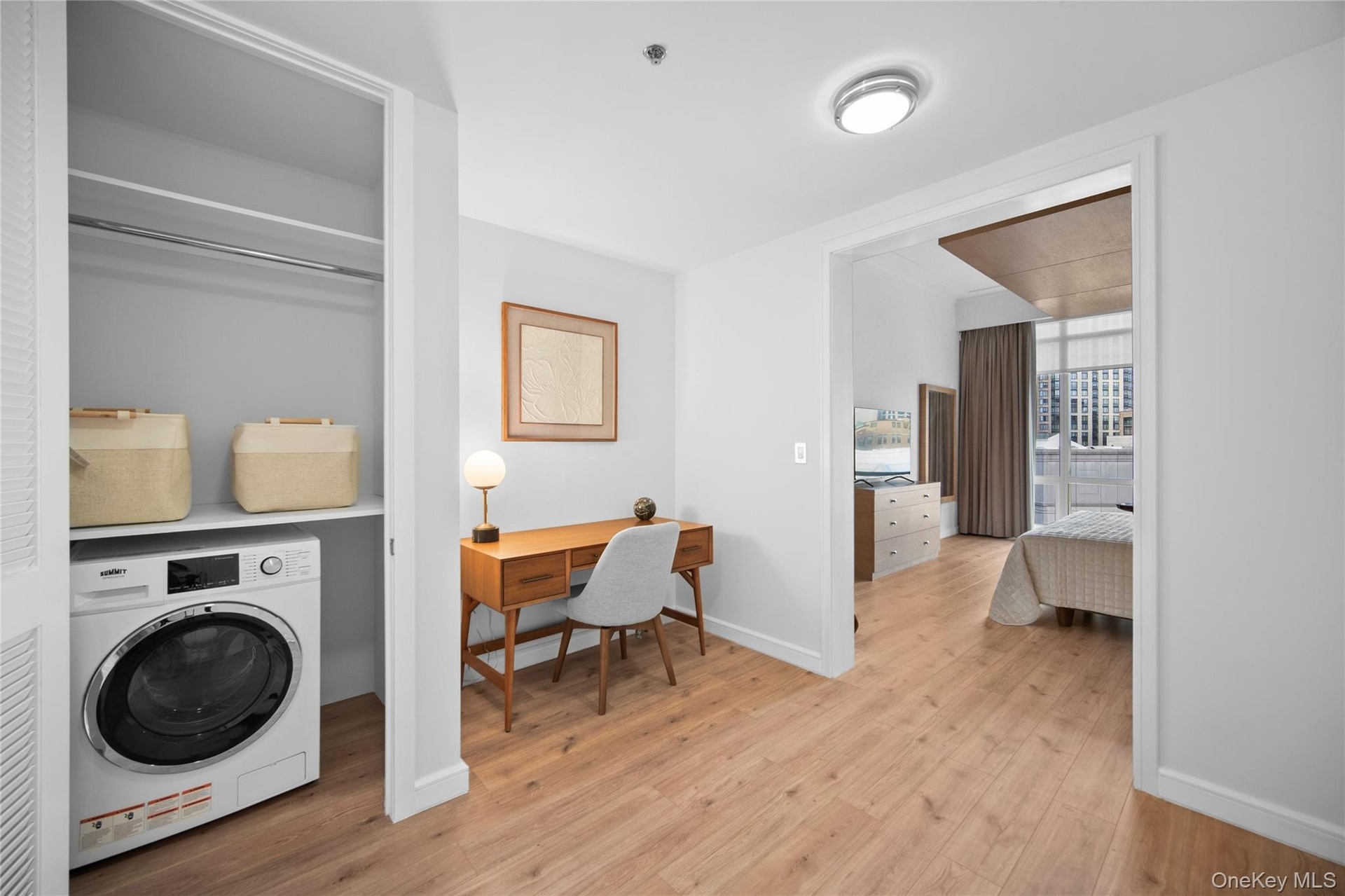 Washroom with washer / clothes dryer, light wood-style floors, and baseboards