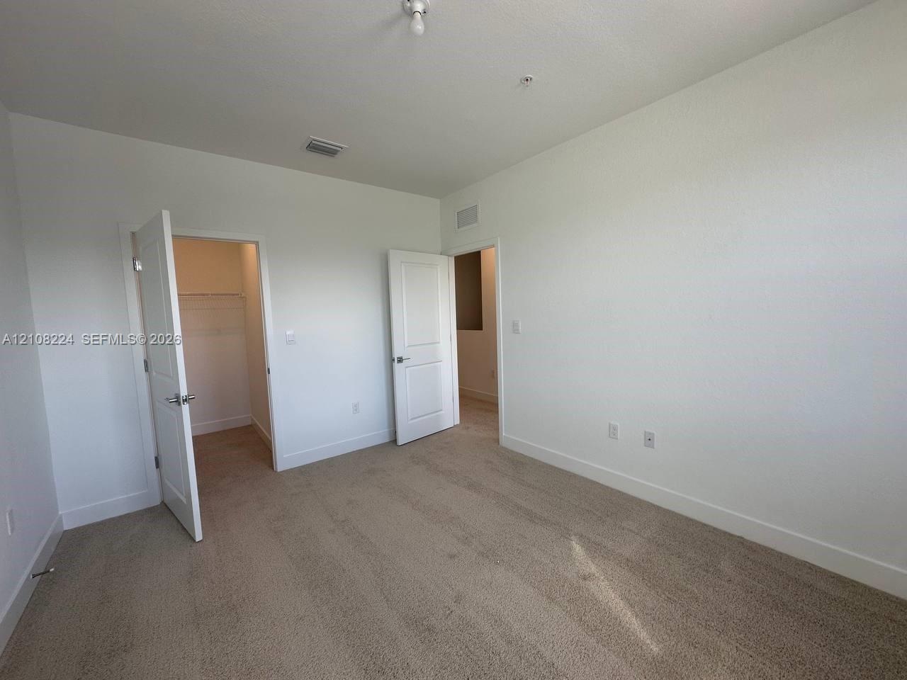 Open-concept living space featuring large-format tile flooring, recessed ceiling lighting, a dedicated kitchen island, and sliding glass patio doors