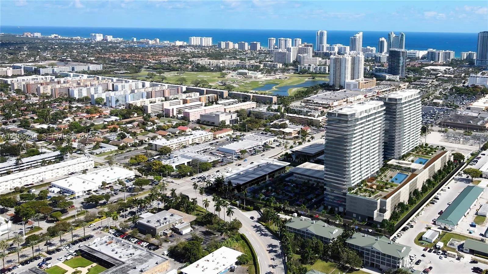 Aerial perspective of high-rise residential towers featuring podium-level swimming pools, landscaped outdoor recreation areas, and proximity to the co