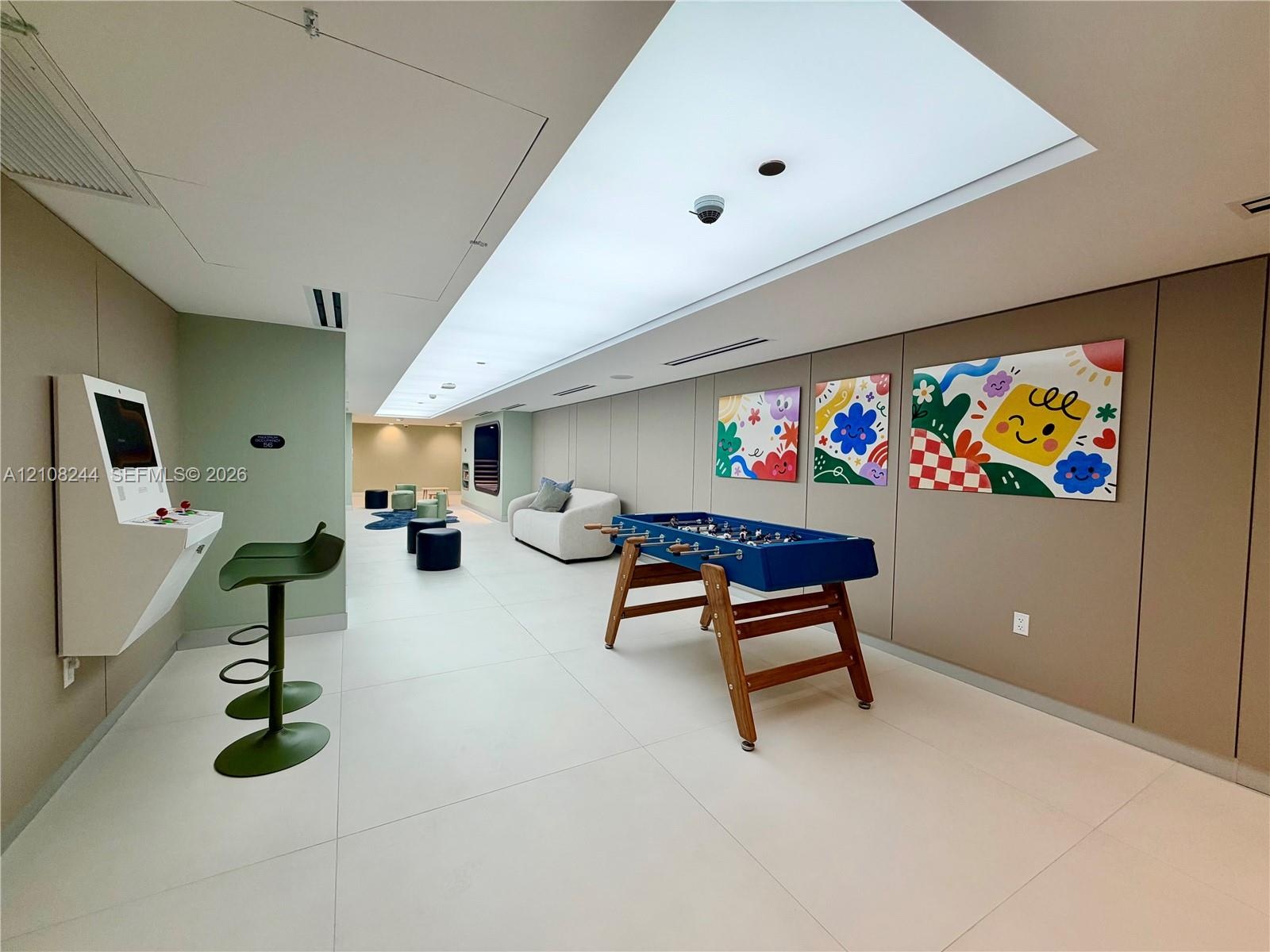 Large-format tile flooring, recessed linear lighting, and wall-mounted multimedia console
