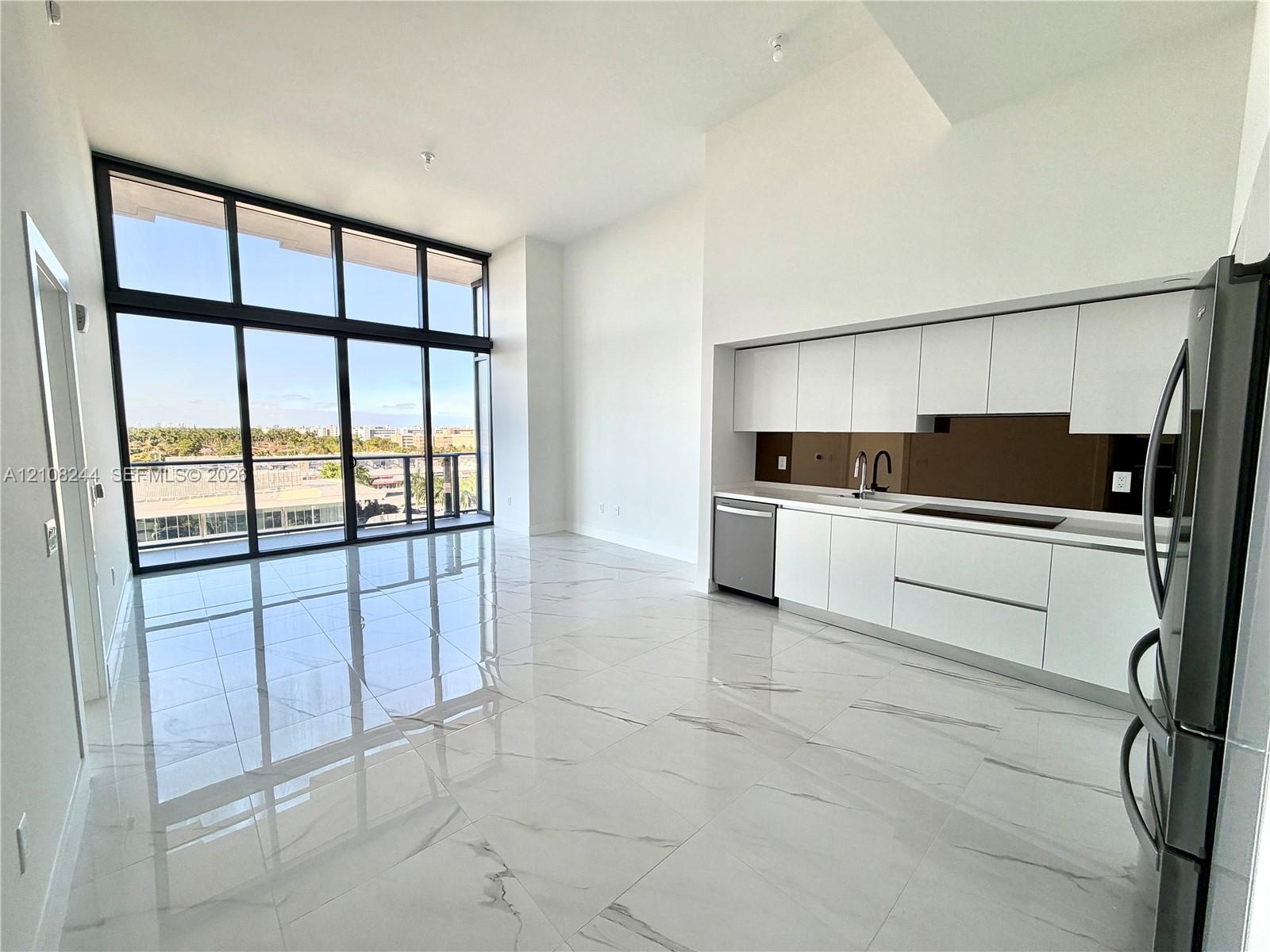 Floor-to-ceiling windows, high ceilings, large-format tile flooring, sleek handleless cabinetry, and contrasting backsplash