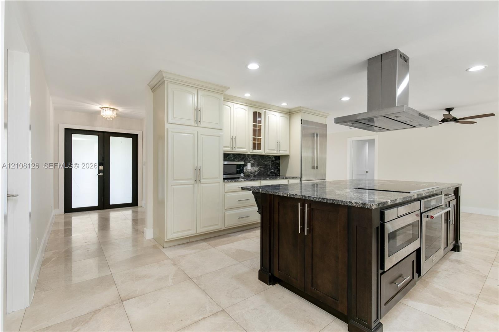 Kitchen featuring an expansive center island with stone countertop, stainless steel professional-grade appliances, built-in cabinetry, polished stone 