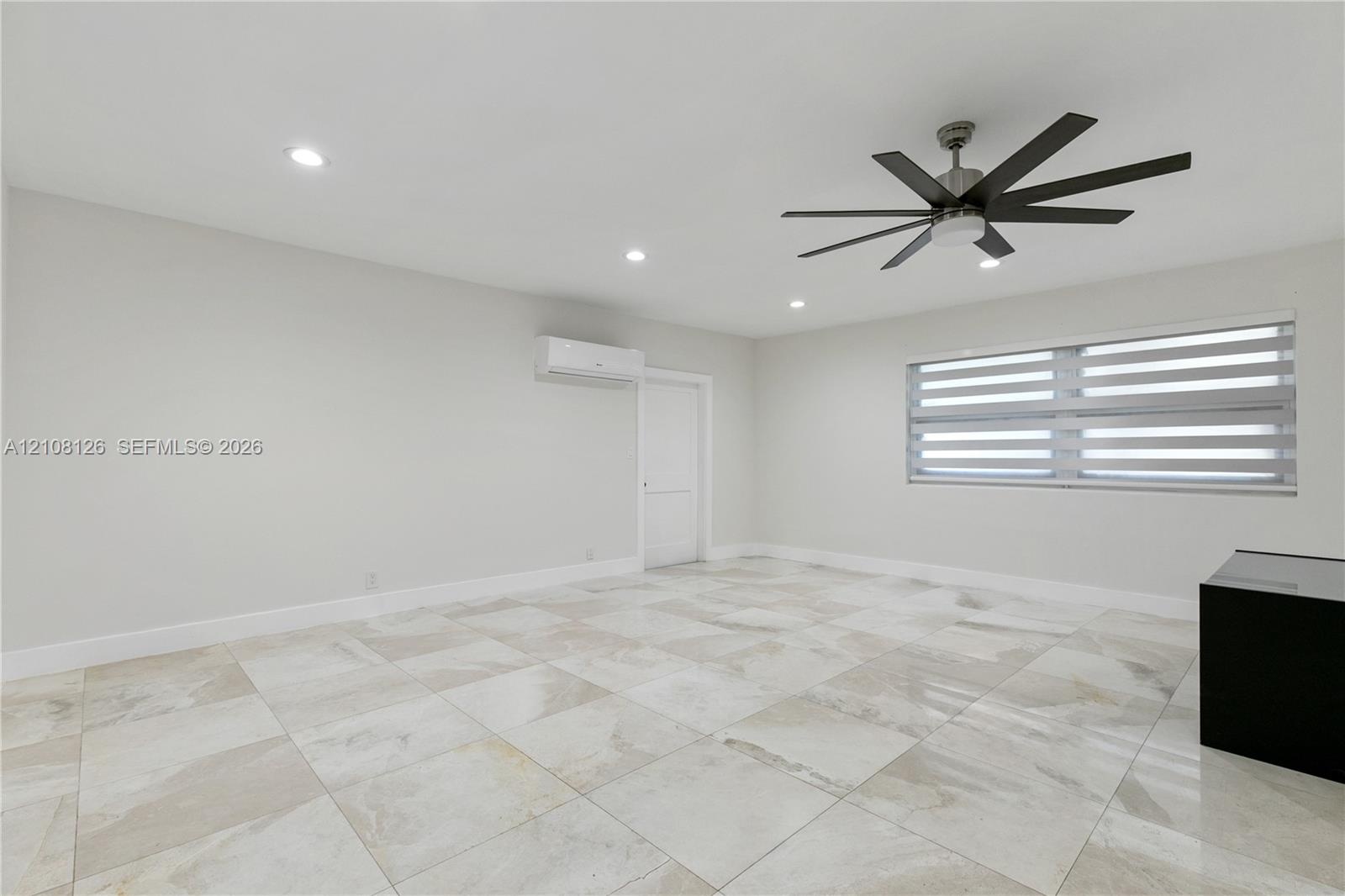 Interior space featuring large-format tile flooring, a multi-blade ceiling fan, recessed lighting, and a wall-mounted climate control unit
