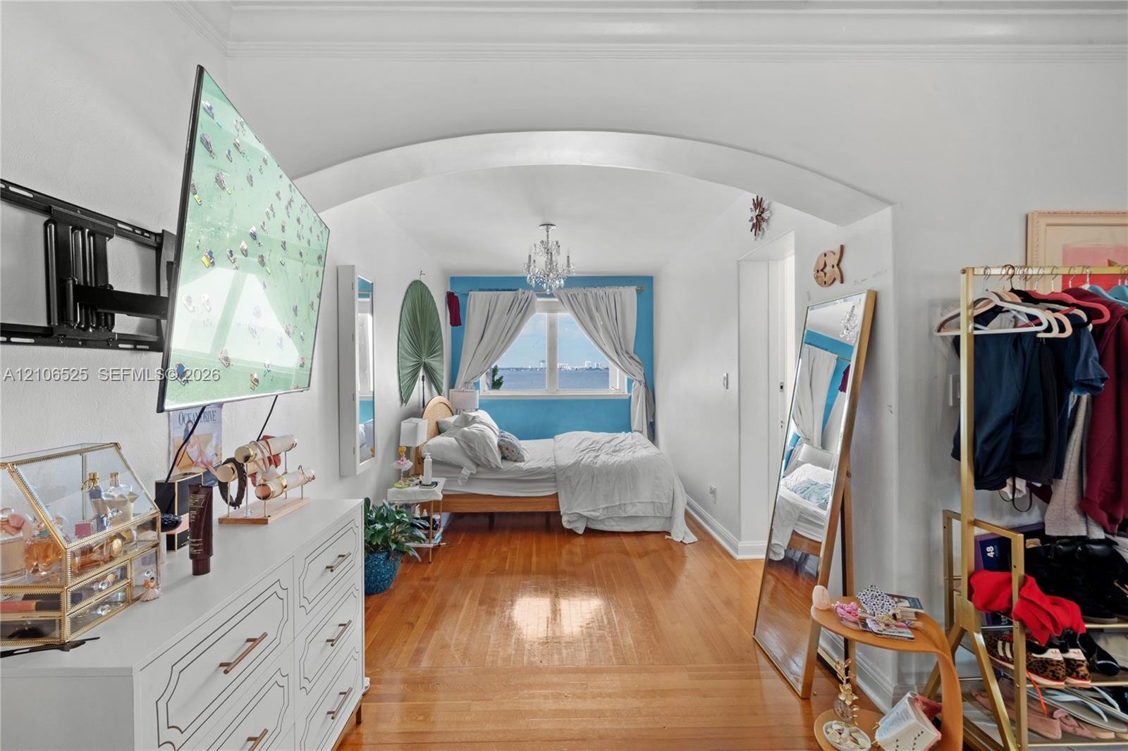 Architectural arched entryway, wood-finish flooring, and ceiling-mounted crystal chandelier