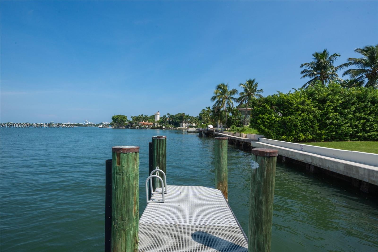 Private waterfront dock with industrial-grade metal decking, timber pilings, and integrated swim ladder, featuring expansive open-water frontage and a