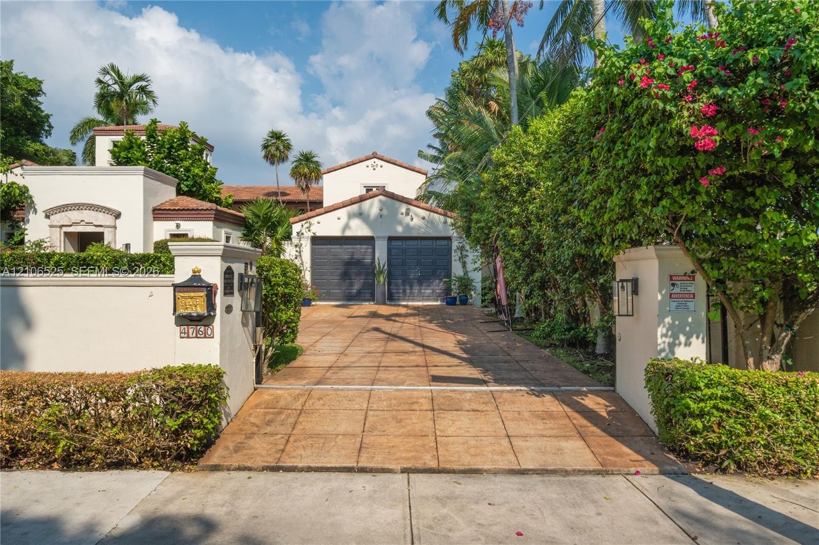 Mediterranean-style stucco exterior featuring a gated entrance, terracotta-tiled roof, paver driveway, and a two-car garage