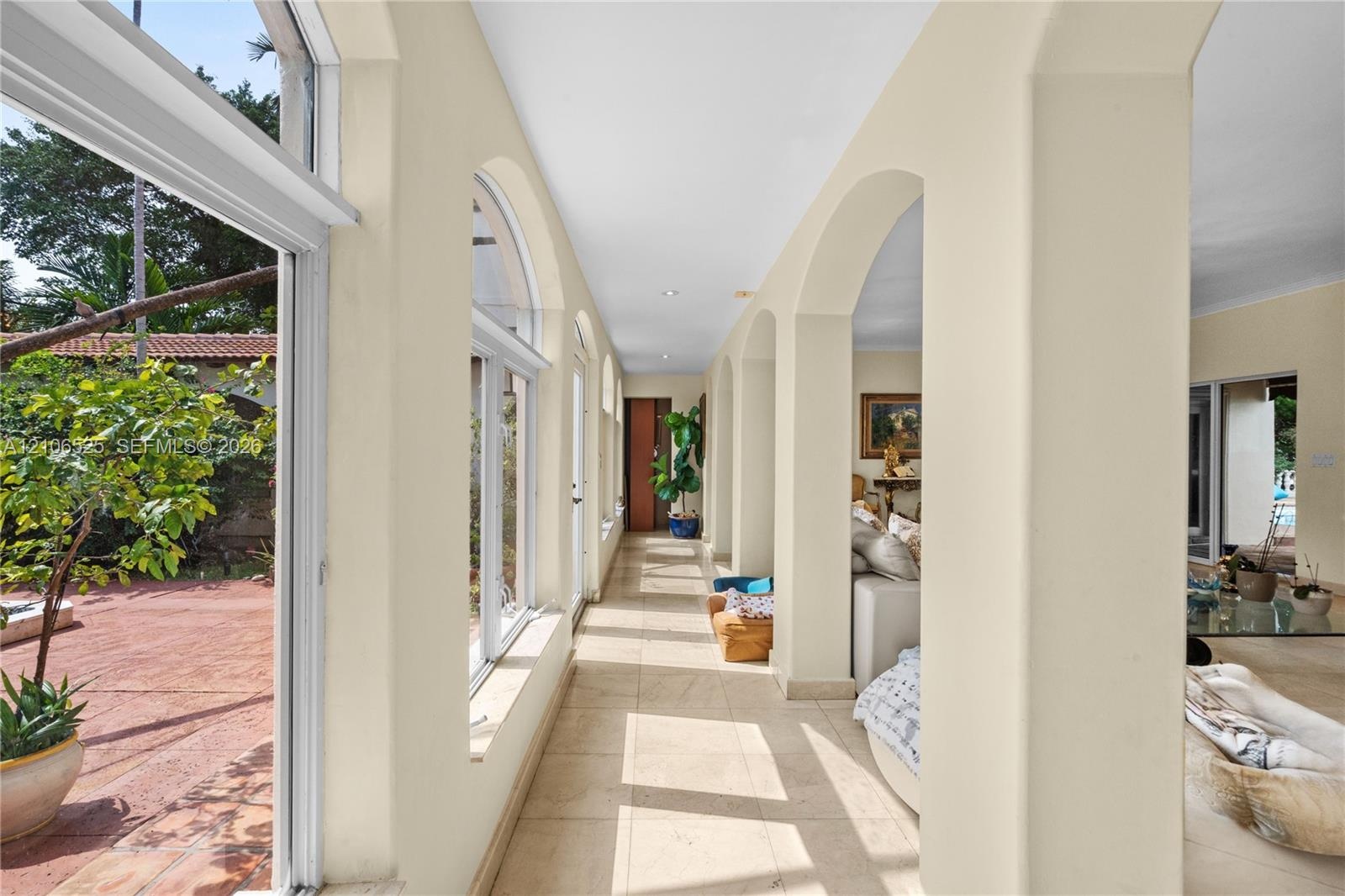 Hallway featuring an arched colonnade, tile flooring, and floor-to-ceiling windows