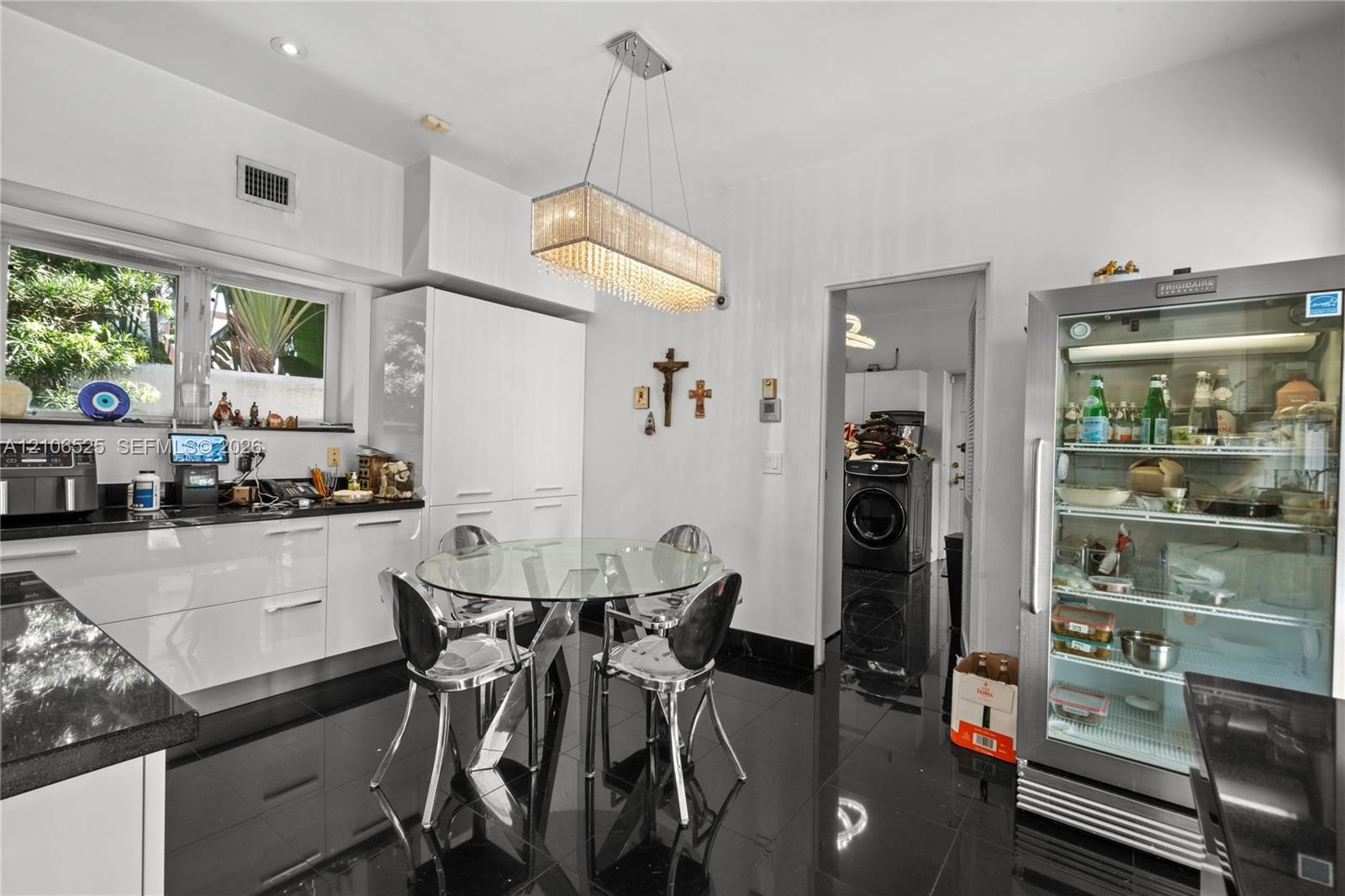 Glossy cabinetry featuring integrated storage, black stone countertops, high-gloss tile flooring, and a rectangular crystal-accented pendant light fix