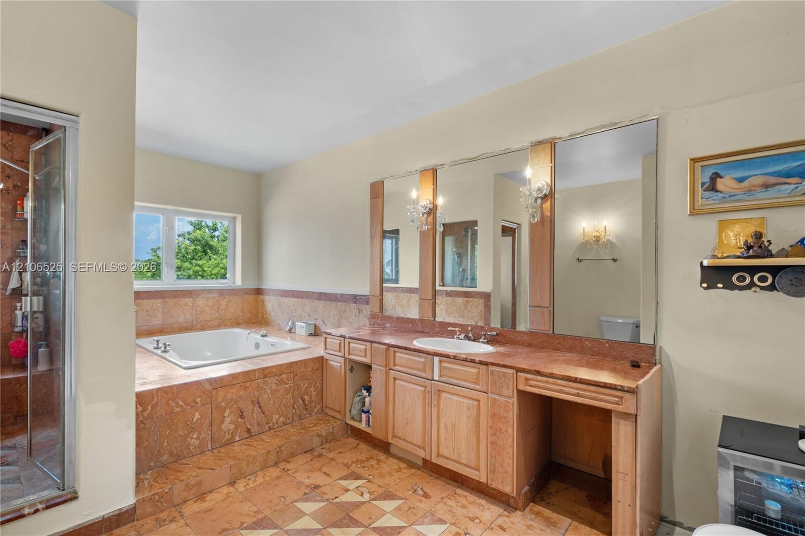 Bathroom featuring a stone-clad jetted soaking tub, custom wood cabinetry with a stone countertop, a recessed vanity area, integrated wall-to-wall mir