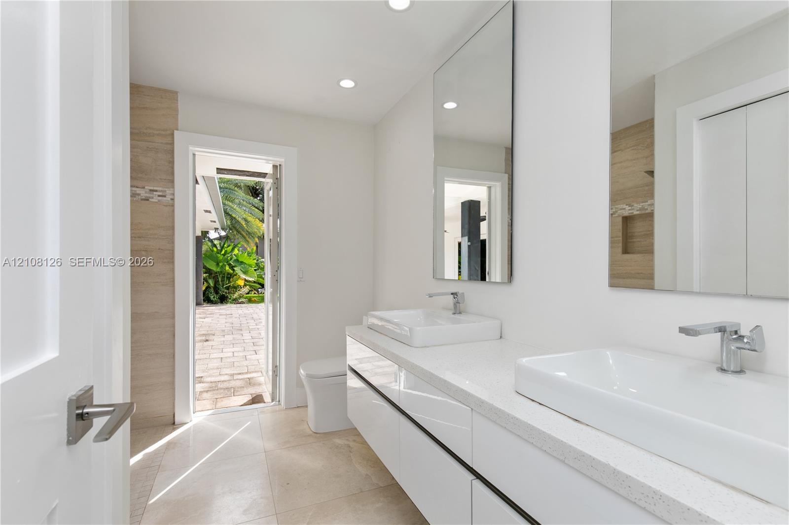 Modern floating vanity with dual rectangular vessel sinks, quartz countertops, and polished chrome faucets, complemented by wall-to-wall mirrors and s
