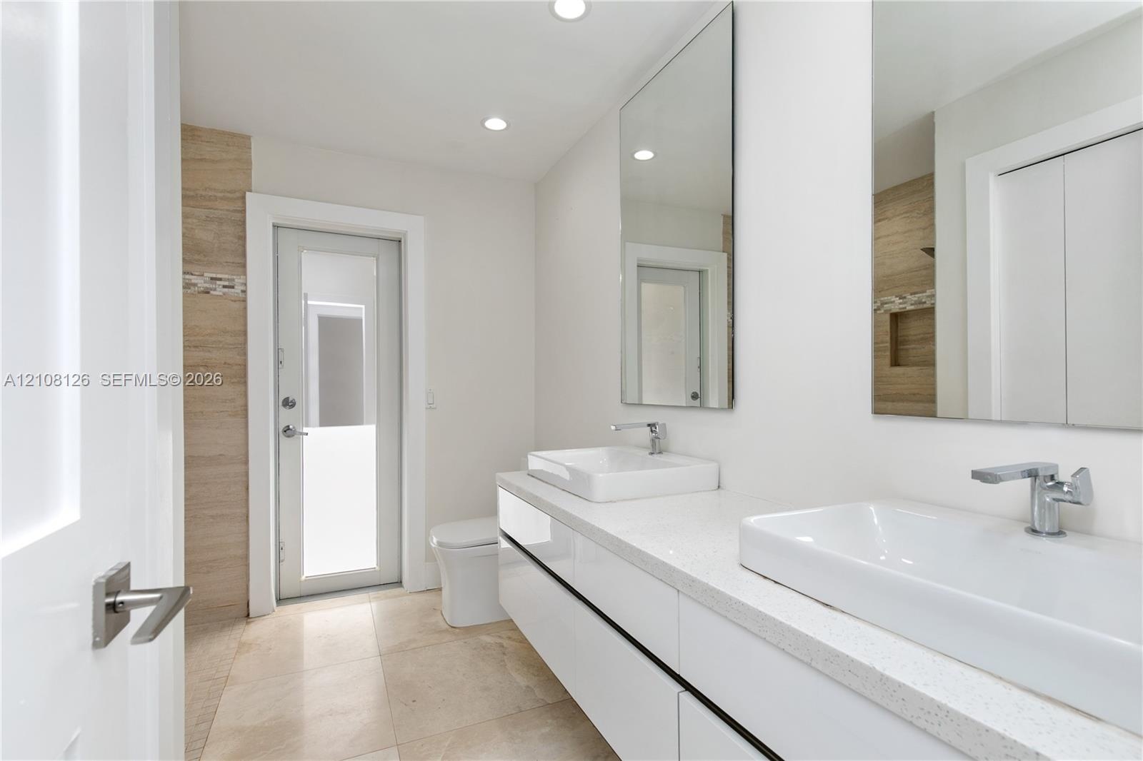 Floating double vanity with rectangular vessel sinks, quartz countertop, chrome faucets, and large-format tile flooring