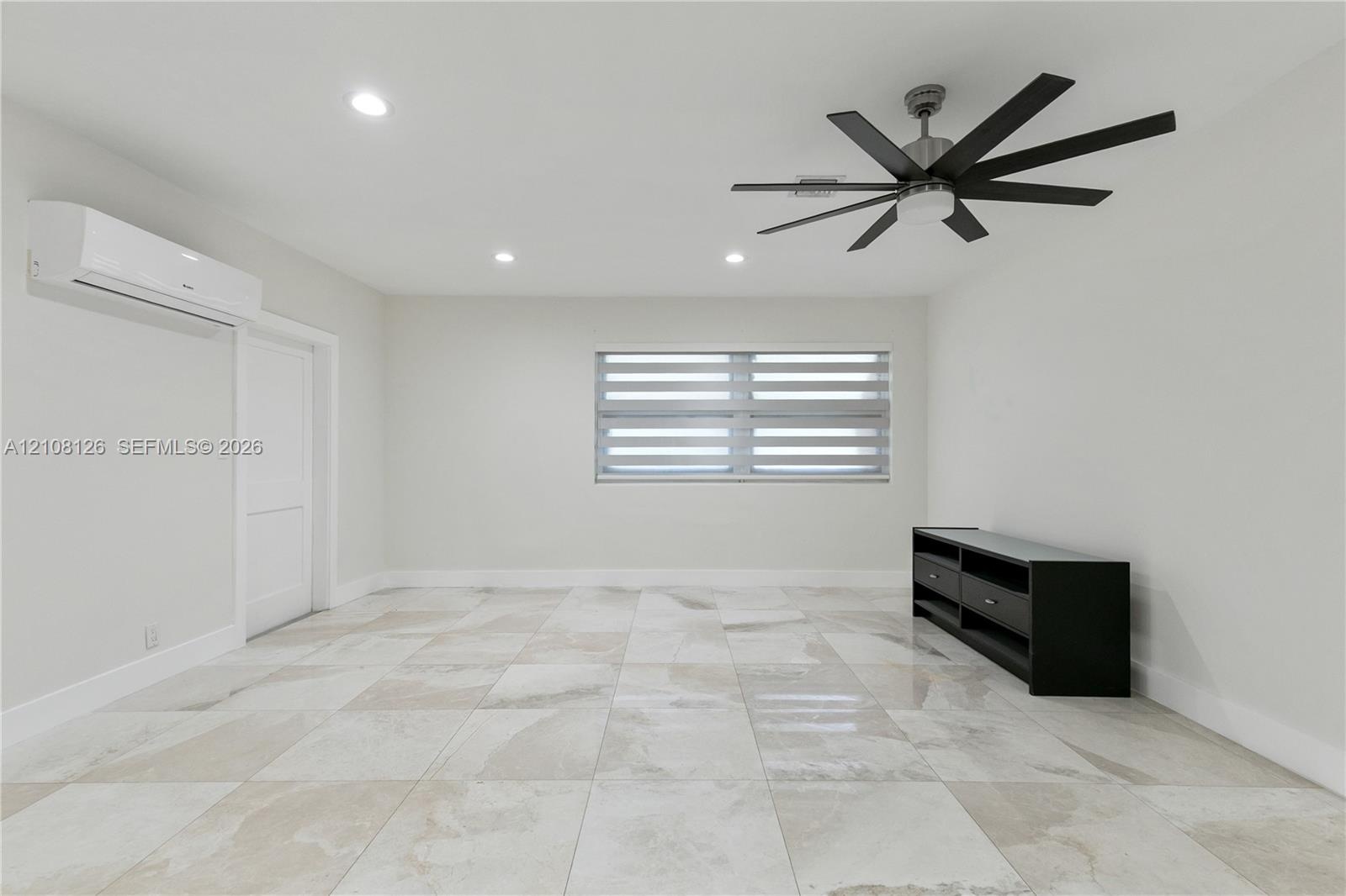 Interior space featuring large-format stone-finish floor tiling, recessed lighting, a multi-blade ceiling fan, a wall-mounted ductless climate control