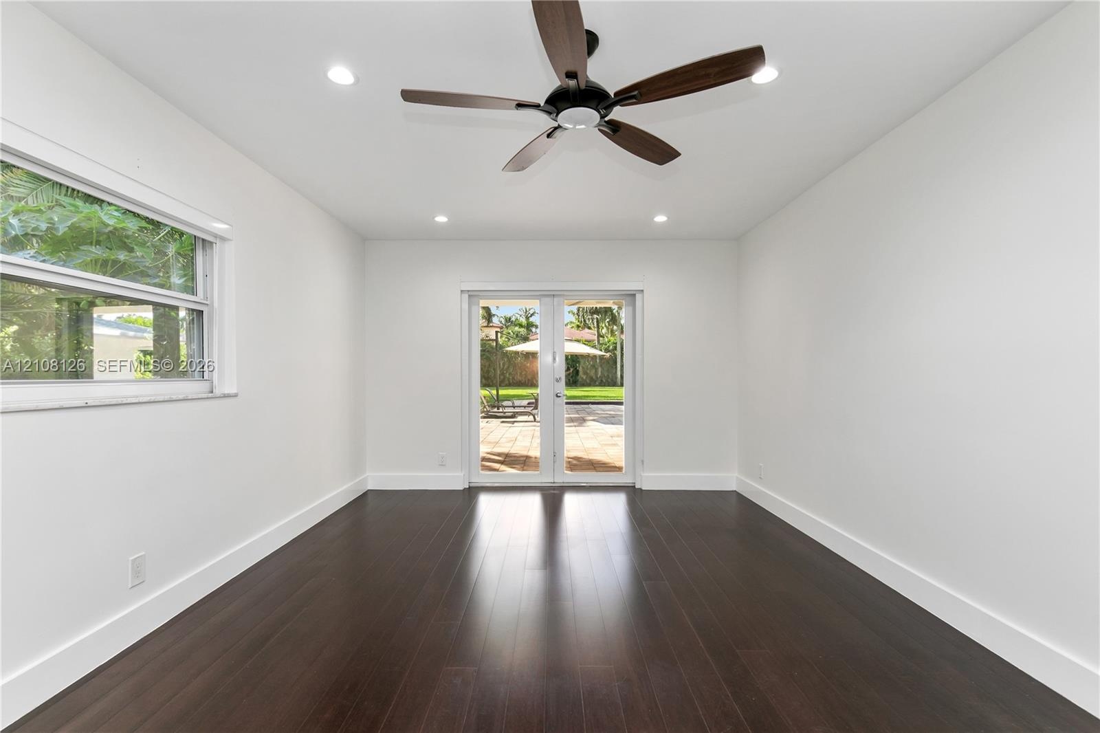 Wood-finish flooring, recessed lighting, dark-toned ceiling fan, and glass-paneled French doors