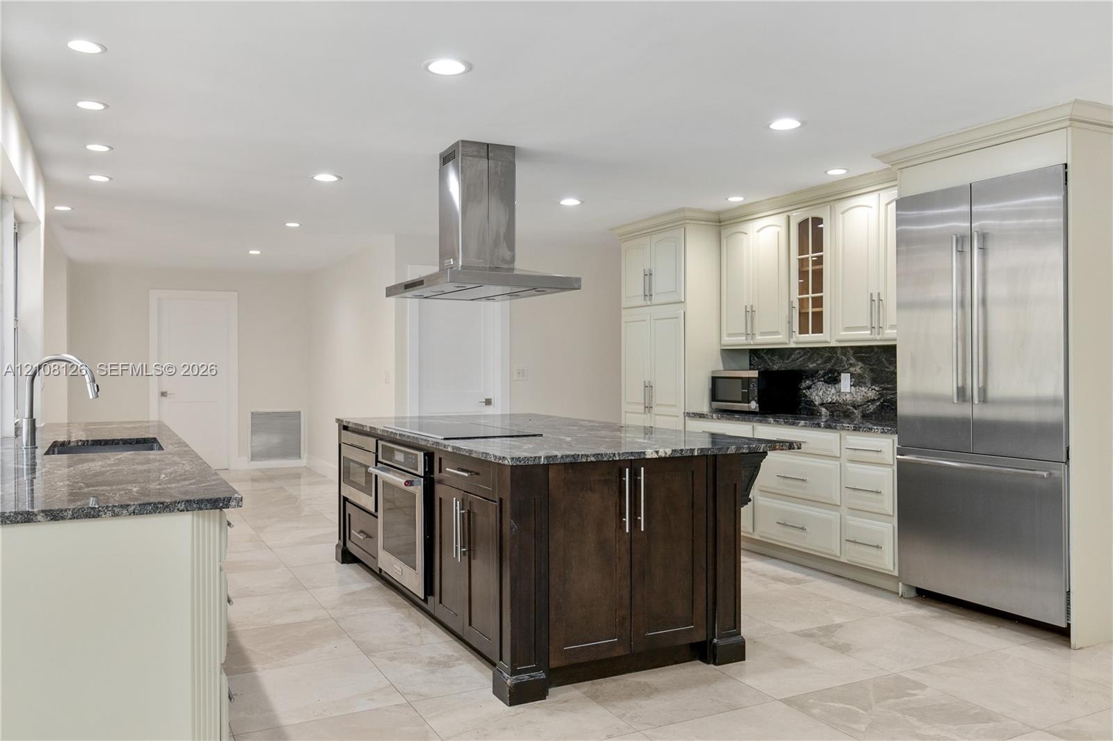 Kitchen featuring a central island with a built-in oven, stone-finish countertops, stainless steel appliances, recessed ceiling lighting, and tile flo