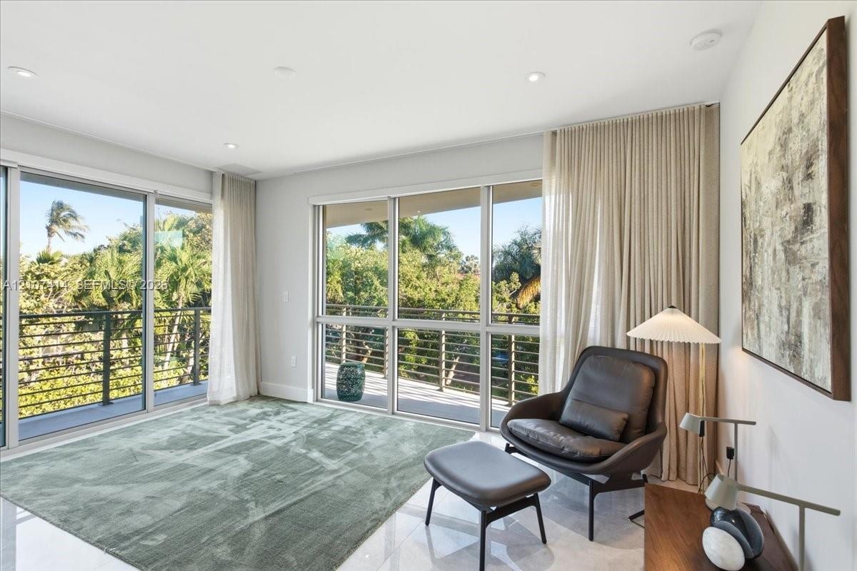 Floor-to-ceiling glass sliding doors, polished tile flooring, recessed ceiling lighting, and a metal-railed balcony