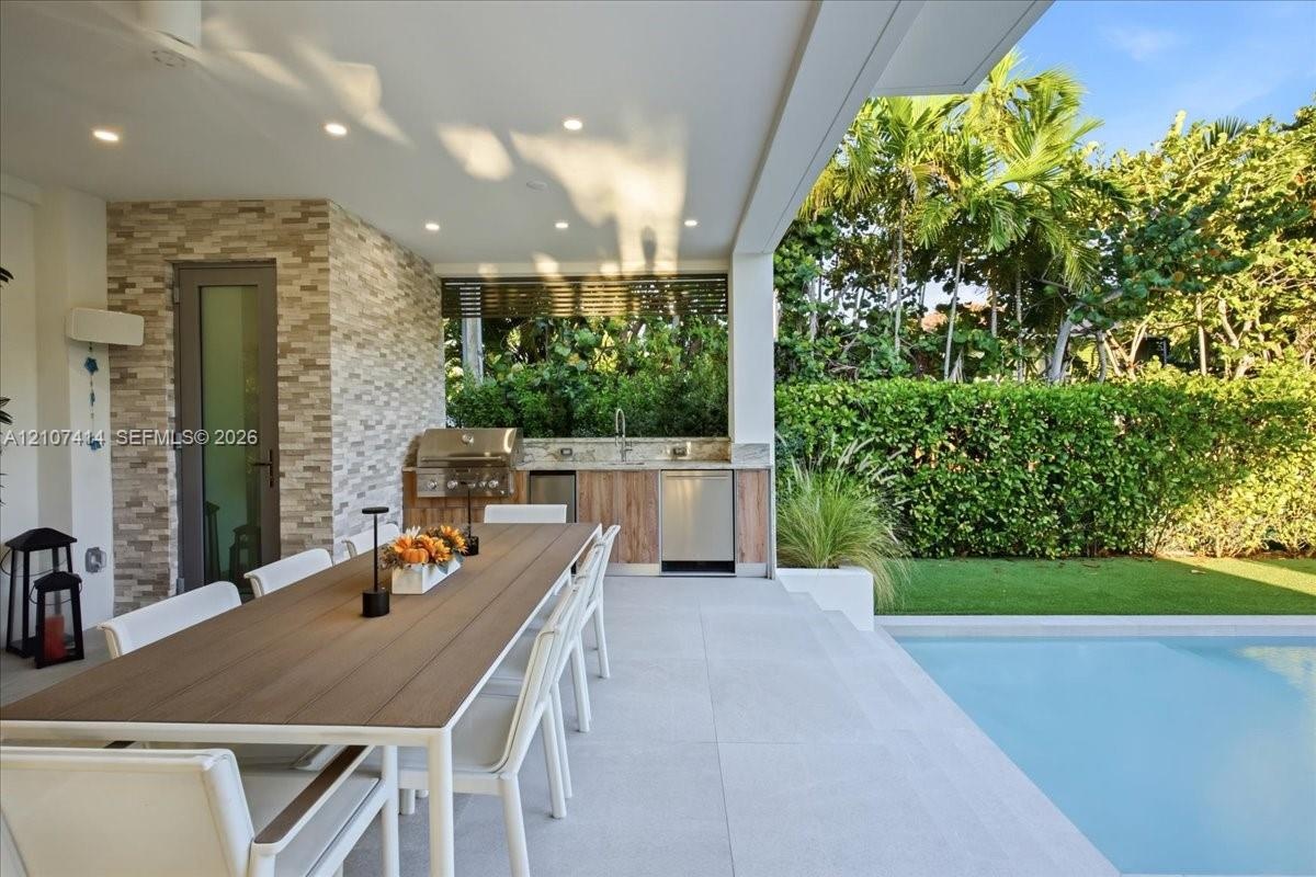 Covered patio featuring an outdoor kitchen with stainless steel appliances, stone-textured wall finish, recessed ceiling lighting, and tile flooring b