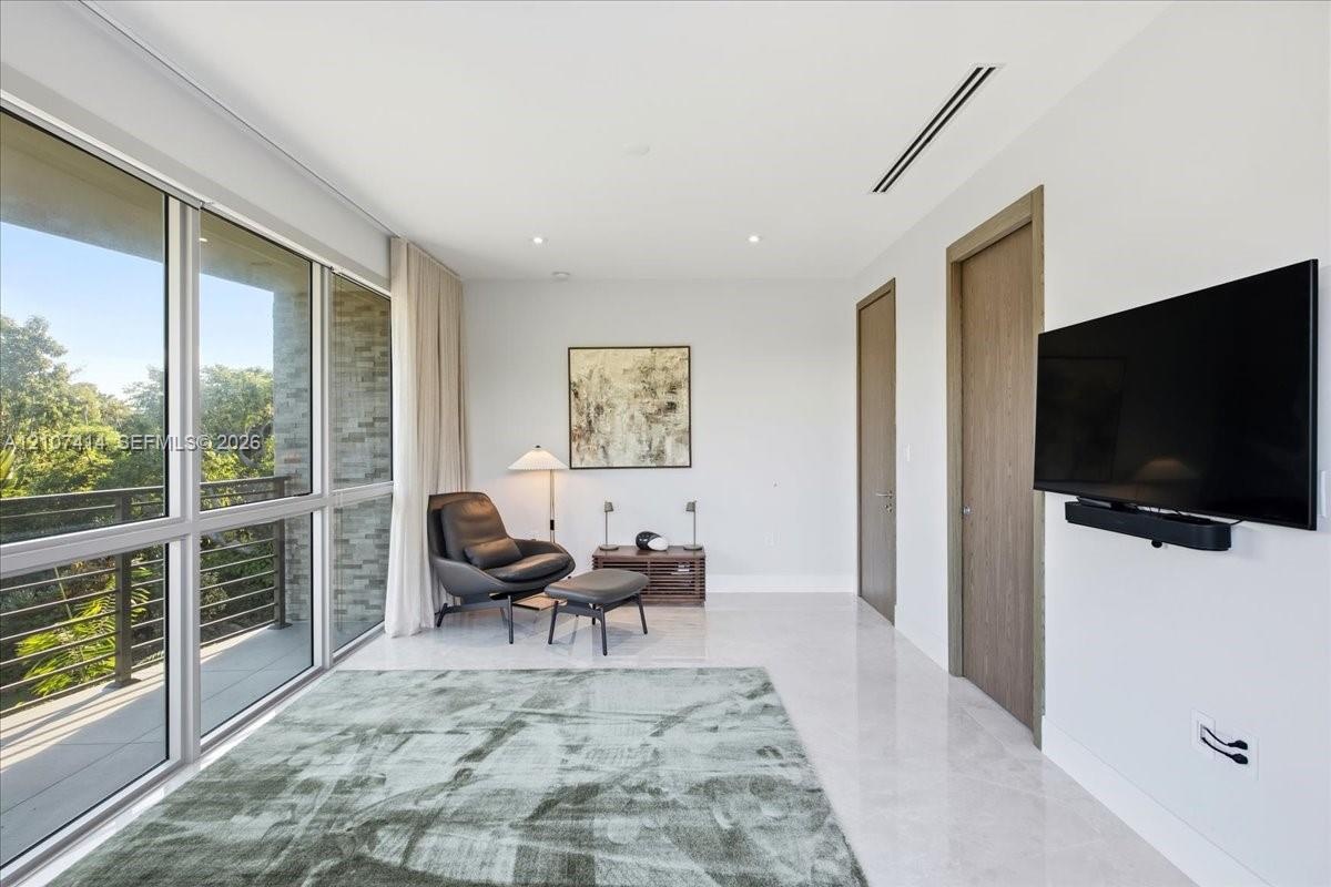 Floor-to-ceiling glass windows, stone flooring, wood-finish interior doors, and a recessed linear ceiling light fixture