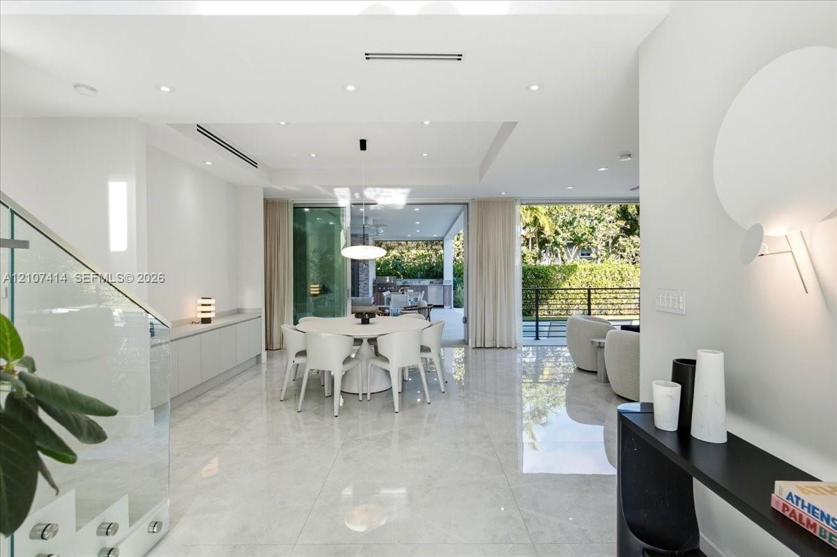 Large-format polished stone flooring, recessed ceiling lighting with tray detail, glass-panel staircase railing, built-in cabinetry, and expansive sli