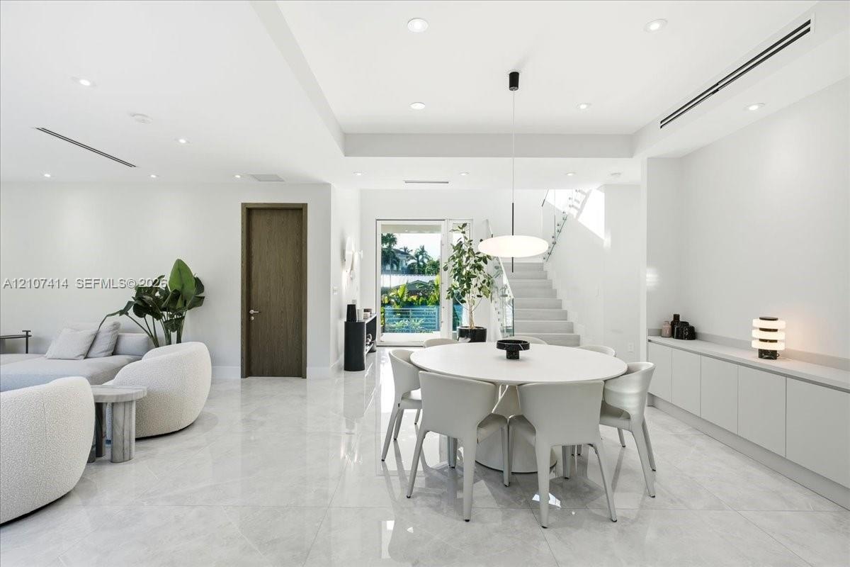 Open-concept interior featuring large-format polished stone flooring, recessed LED lighting, built-in cabinetry with a stone countertop, a modern pend