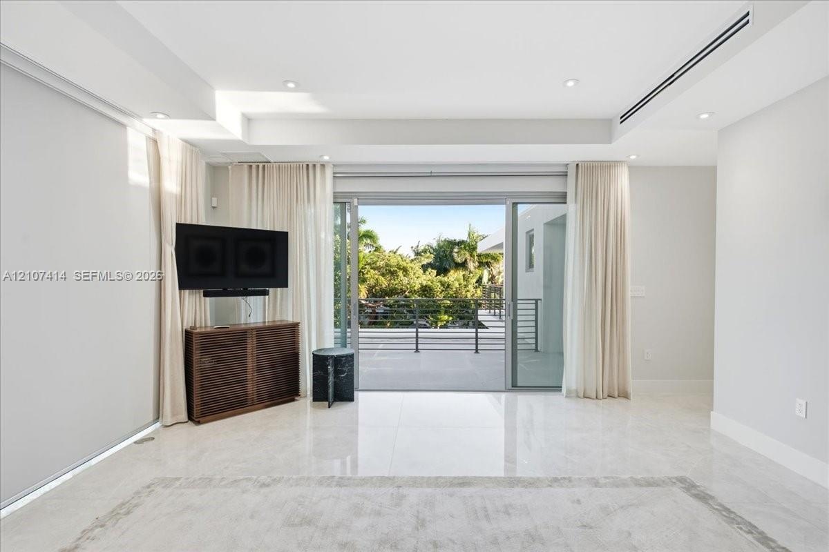 Interior space featuring polished stone flooring, recessed ceiling lighting, a linear HVAC diffuser, and expansive multi-panel sliding glass doors ope