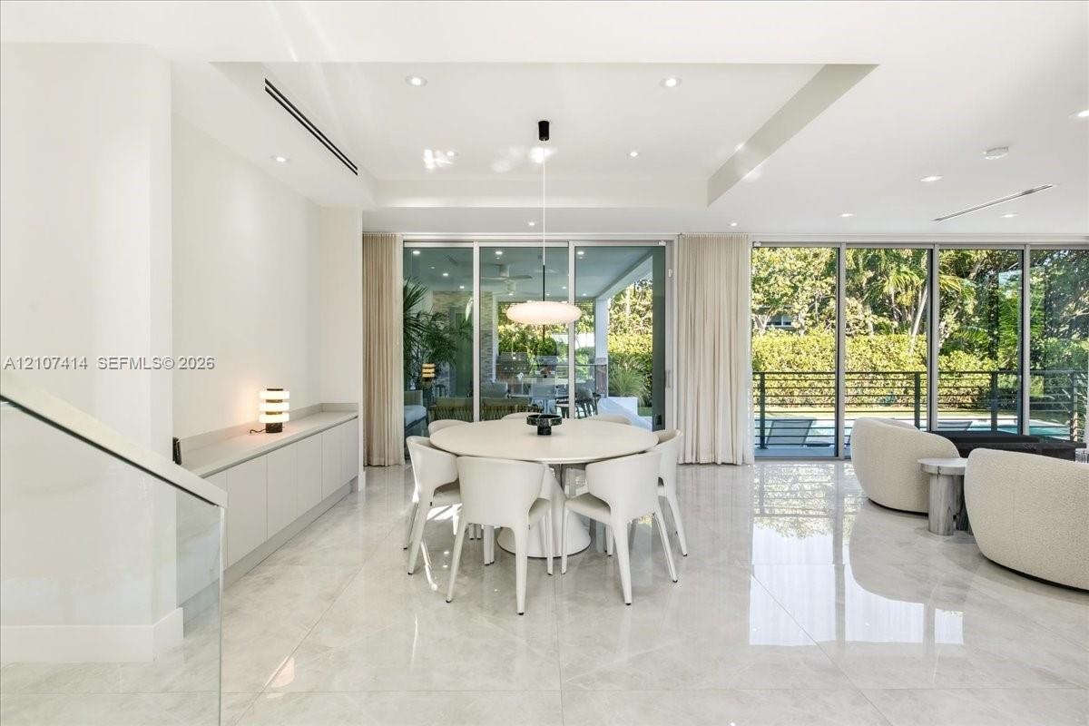 Open-concept interior featuring large-format tile flooring, floor-to-ceiling glass sliding doors, recessed lighting, and custom built-in cabinetry wit