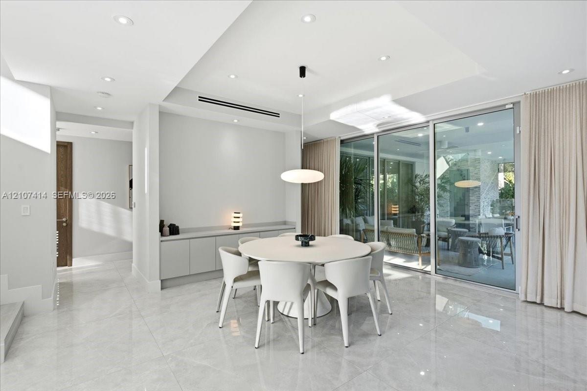 Polished stone-finish flooring, built-in wall cabinetry, recessed ceiling lighting, a modern pendant light fixture, and floor-to-ceiling sliding glass