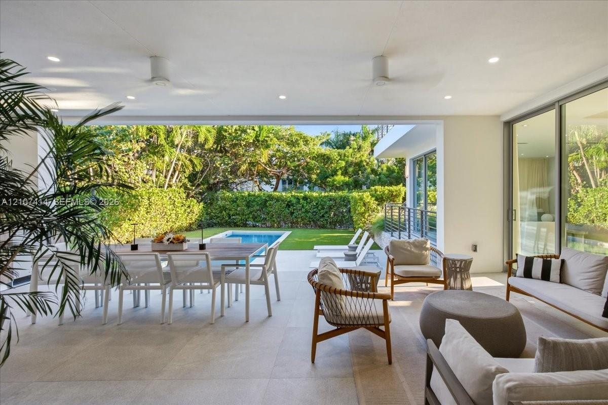 Covered patio featuring large-format stone-finish flooring, recessed lighting, ceiling fans, floor-to-ceiling glass sliding doors, and direct access t