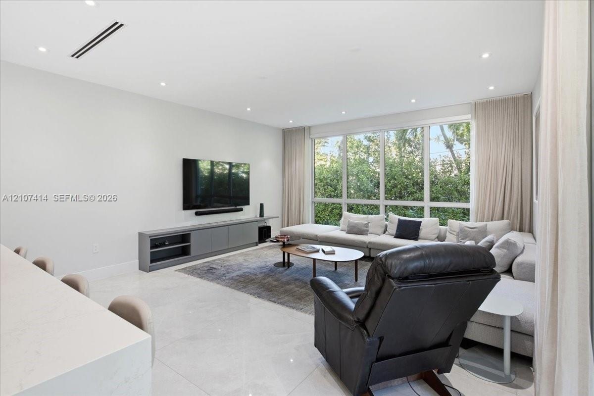 Living area featuring recessed ceiling lighting, linear air diffusers, large-format tile flooring, built-in cabinetry, and floor-to-ceiling windows