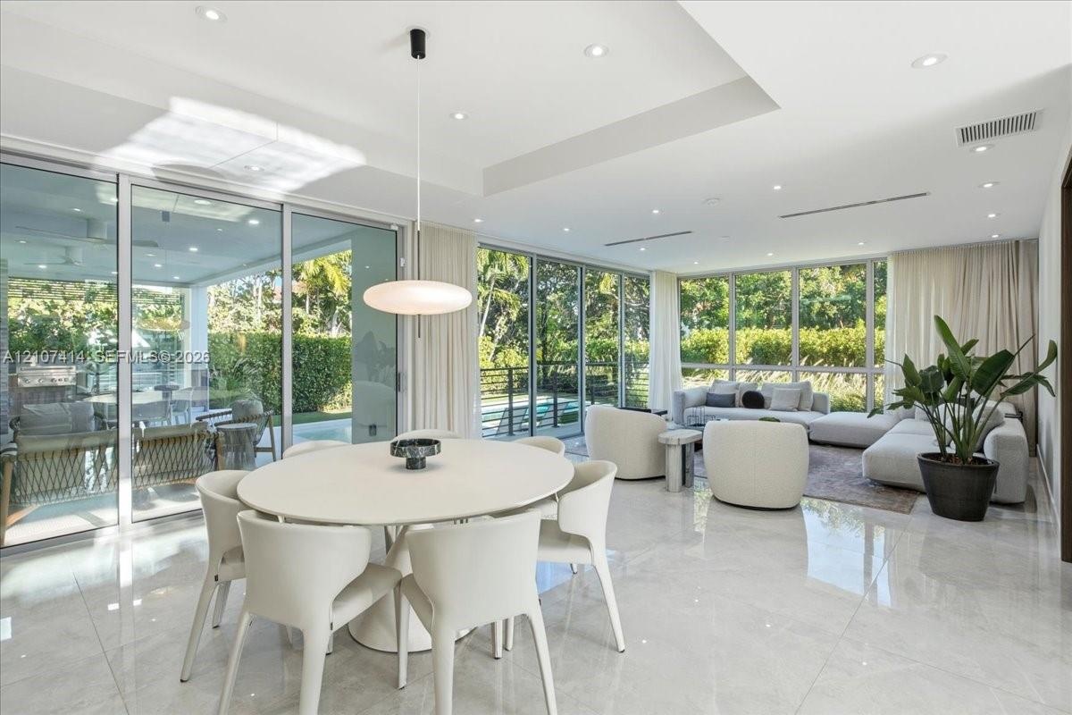 Open-concept interior featuring large-format tile flooring, recessed ceiling lighting, a tray ceiling detail, and floor-to-ceiling glass sliding doors