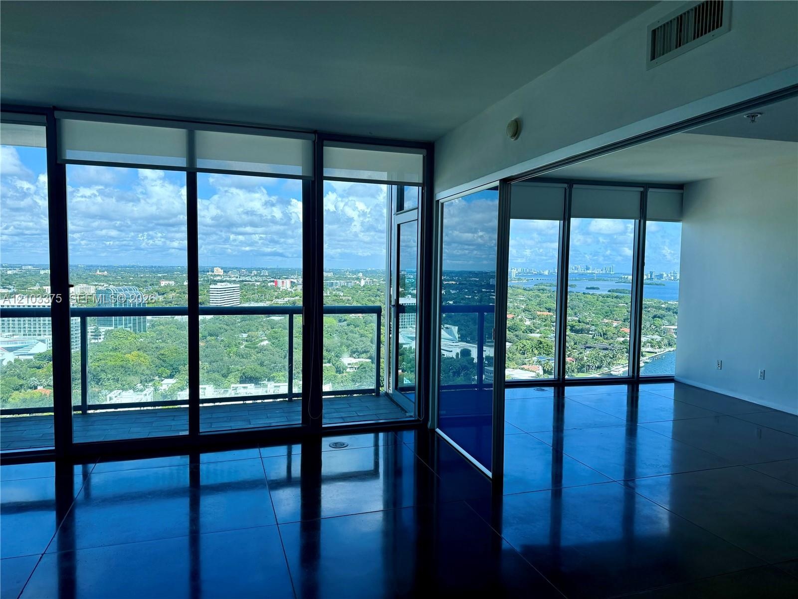 Floor-to-ceiling glass windows, polished concrete flooring, expansive balcony, and panoramic exterior scenery