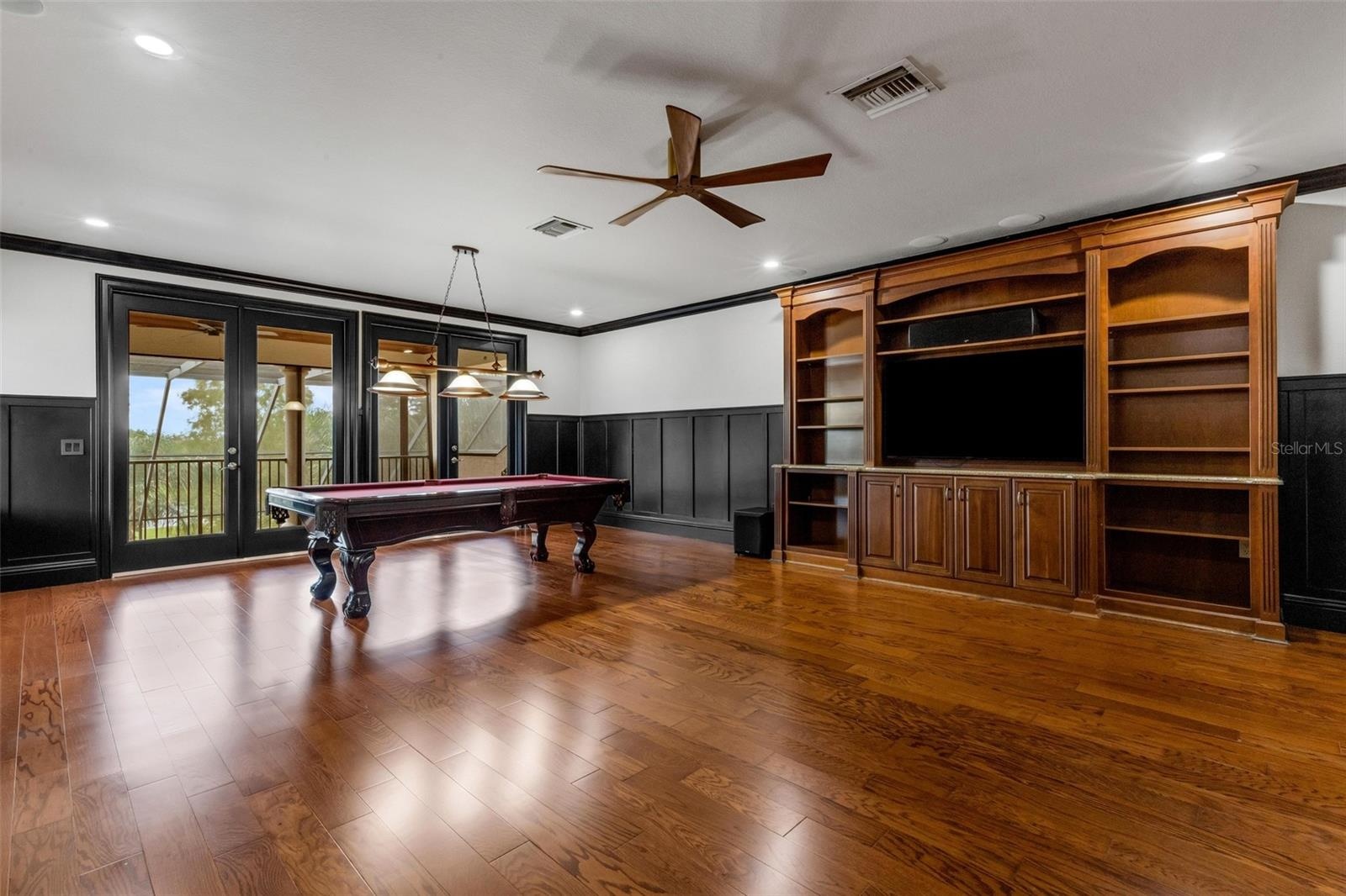 The built-in entertainment system, custom wainscoting all around and two sets of glass doors that open to the balcony.