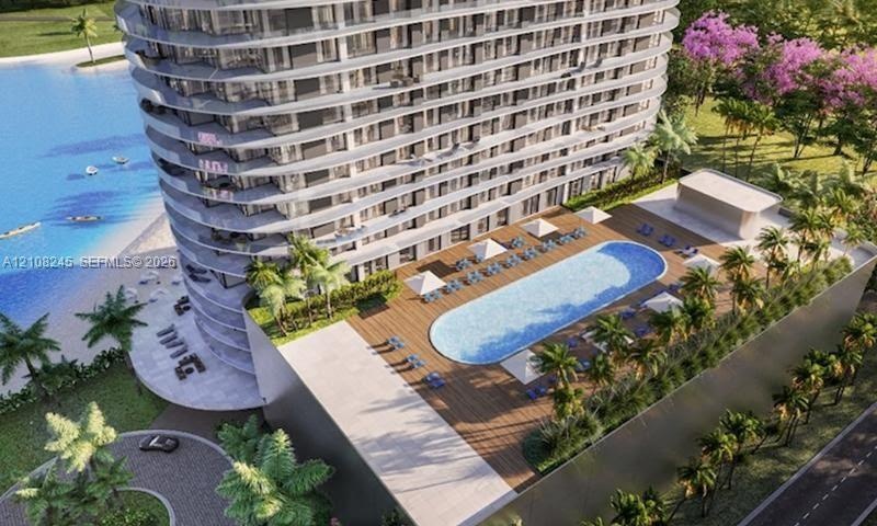 High-rise residential building featuring curved balconies, an elevated swimming pool with wood-finish decking, and landscaped grounds with mature palm