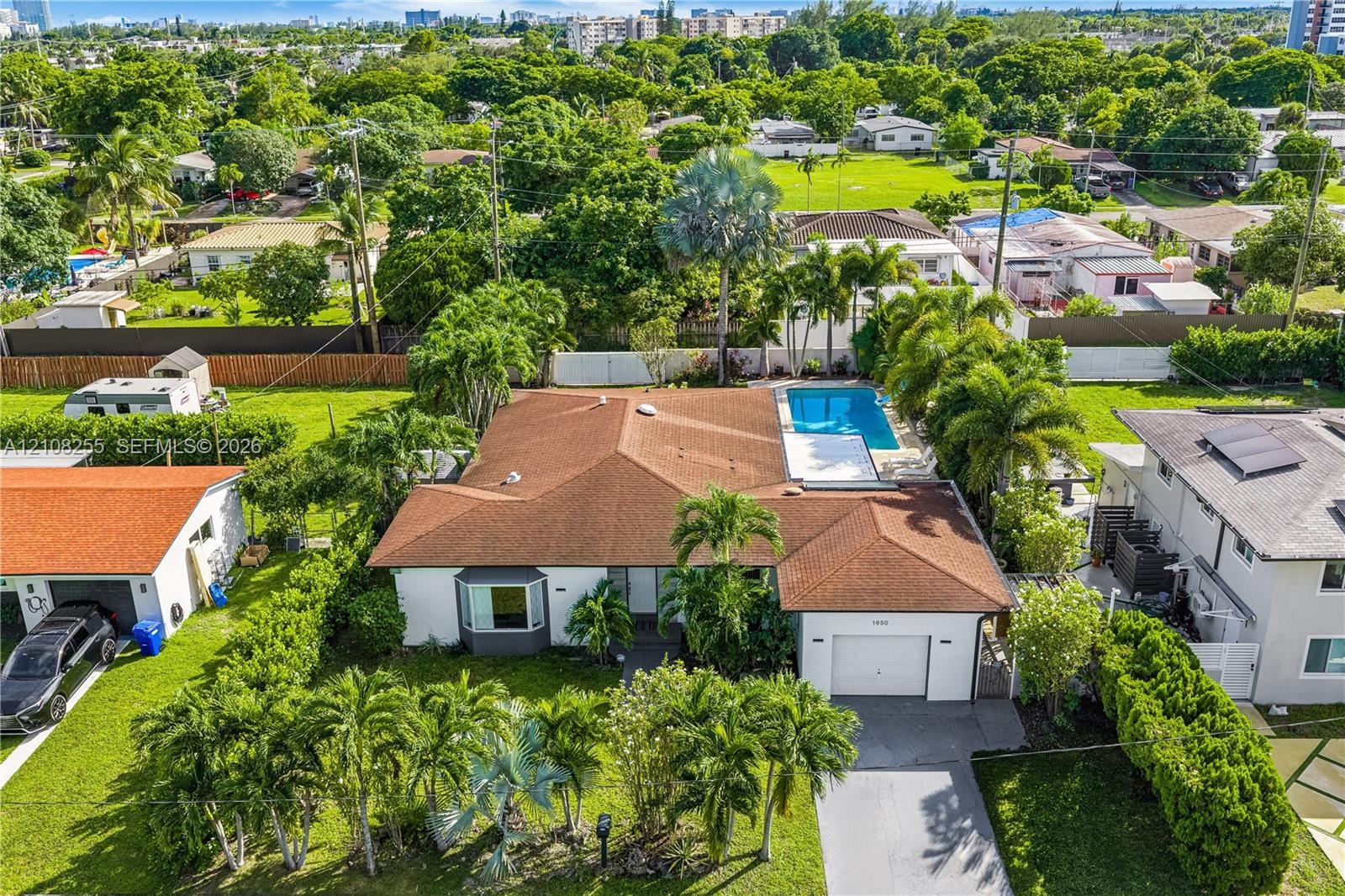 Single-story residence featuring a hipped roof, attached garage, bay window, and a rear swimming pool set within a manicured landscape