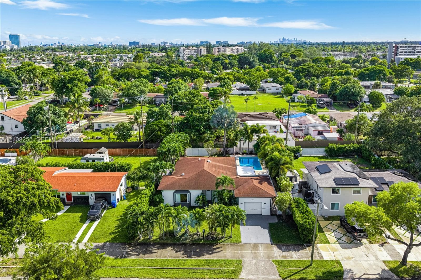 Single-story residence featuring a tile roof, built-in swimming pool, paved driveway, and mature landscaping