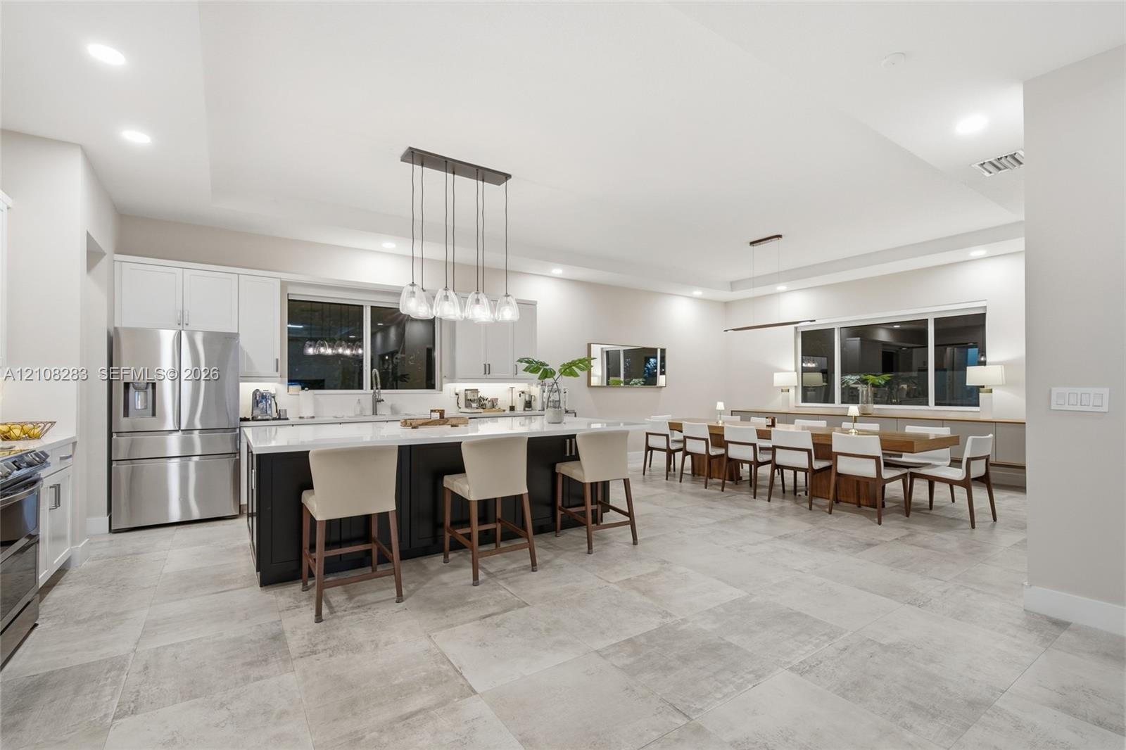 Kitchen featuring a center island with contrasting cabinetry, stone-finish countertops, stainless steel appliances, recessed ceiling lighting, and lar