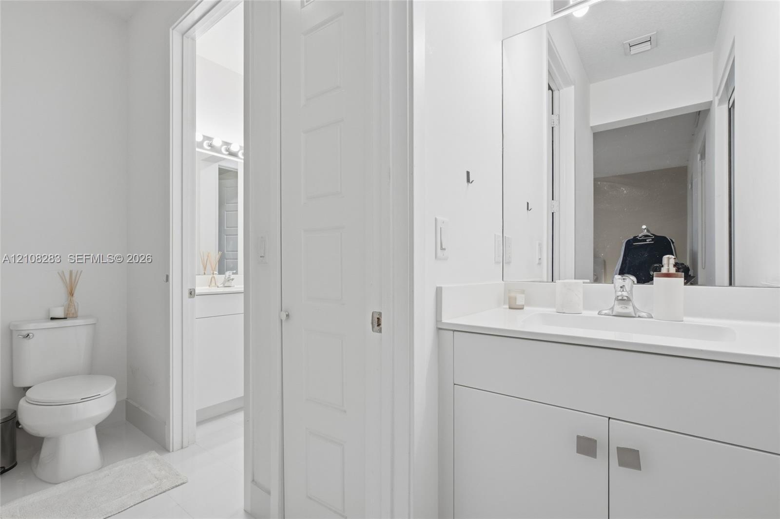 Bathroom featuring a white vanity cabinet with a stone-top integrated sink, a full-height wall mirror, a polished chrome faucet, and a standard-height
